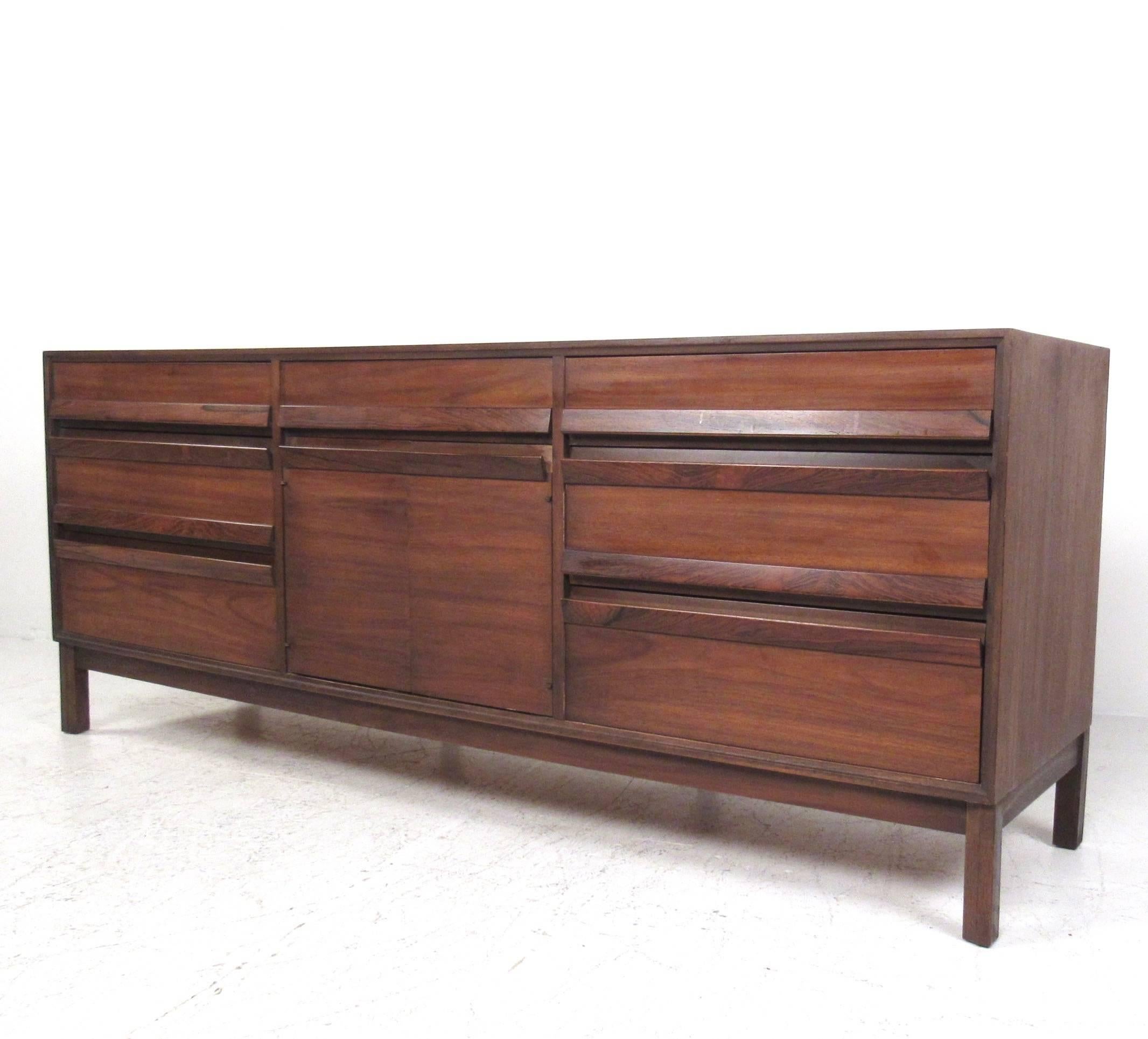 This vintage modern dresser features subtle sculpted rosewood drawer handles, rich walnut finish with, and quality Mid-Century construction. The large size and spacious storage contained within make this dresser the perfect addition to any interior.