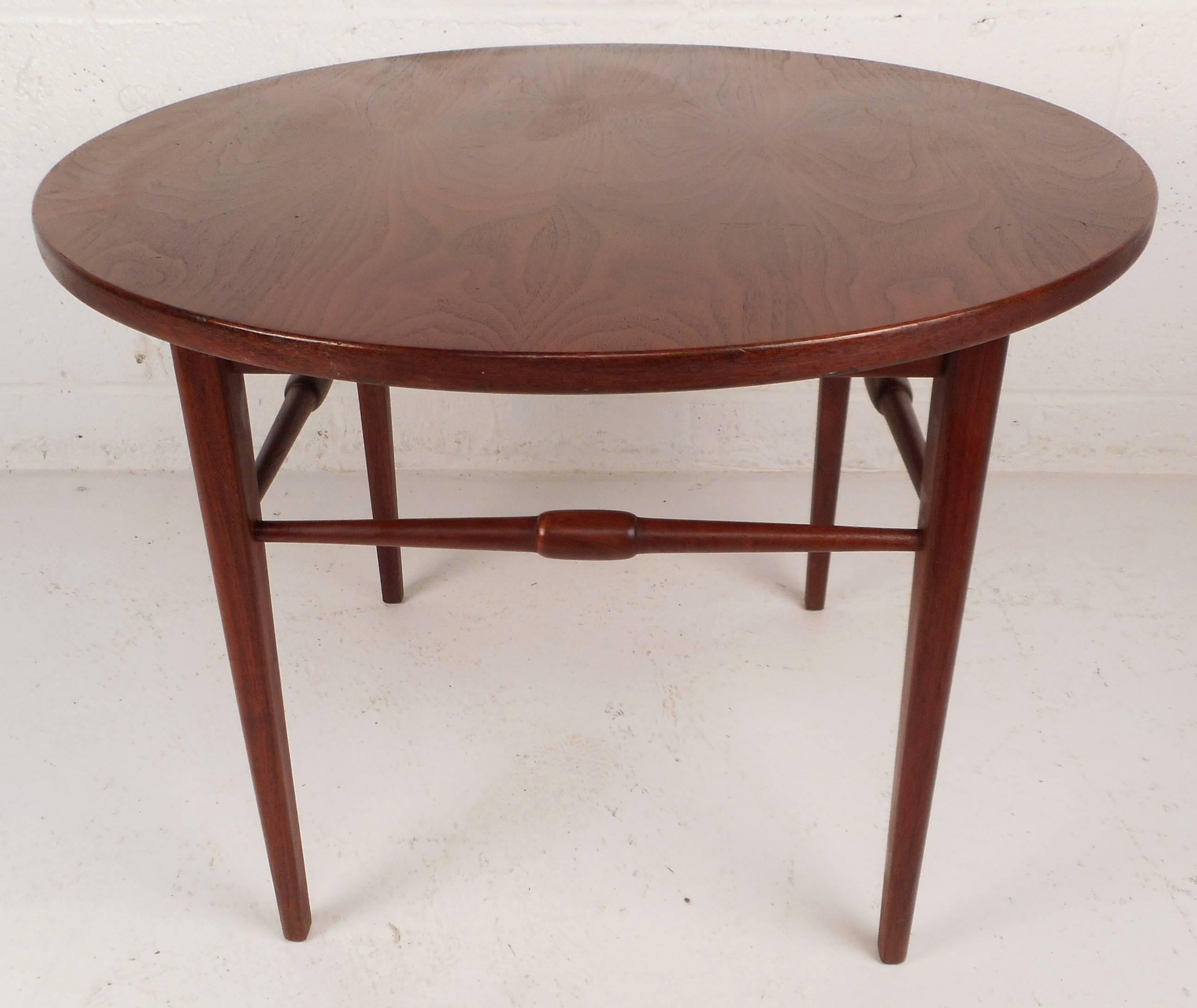 Gorgeous vintage modern round end table features unique sculpted stretchers between each leg. Stunning wood grain and sleek tapered legs show quality craftsmanship. Stylish design makes the perfect addition to any modern interior. Please confirm