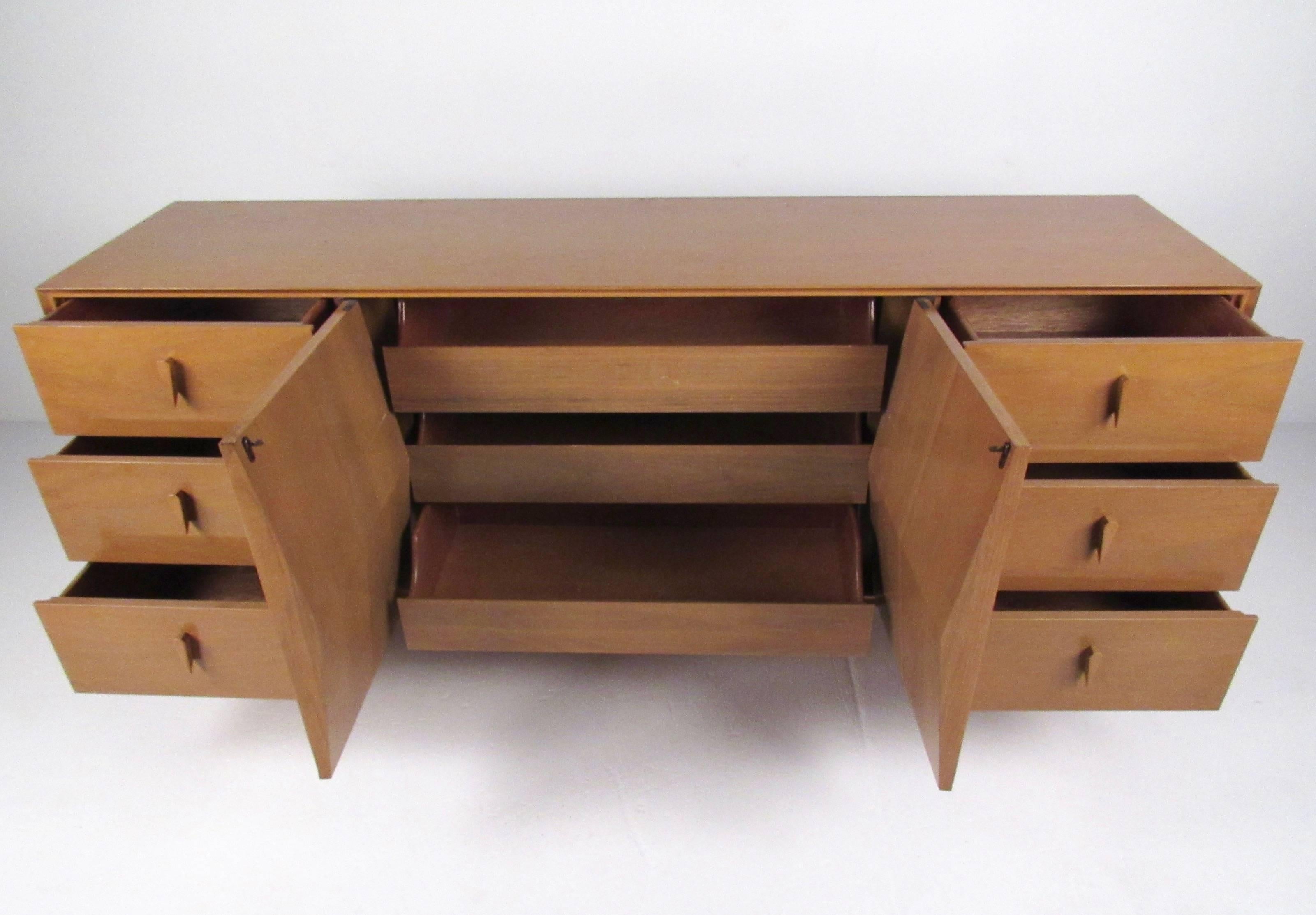 This beautiful diamond front dresser features three wide center drawers contained behind sculpted diamond front doors. Unique drawer pulls and brass tipped tapered legs add to the mid-century style of this vintage Albert Parvin bedroom dresser.