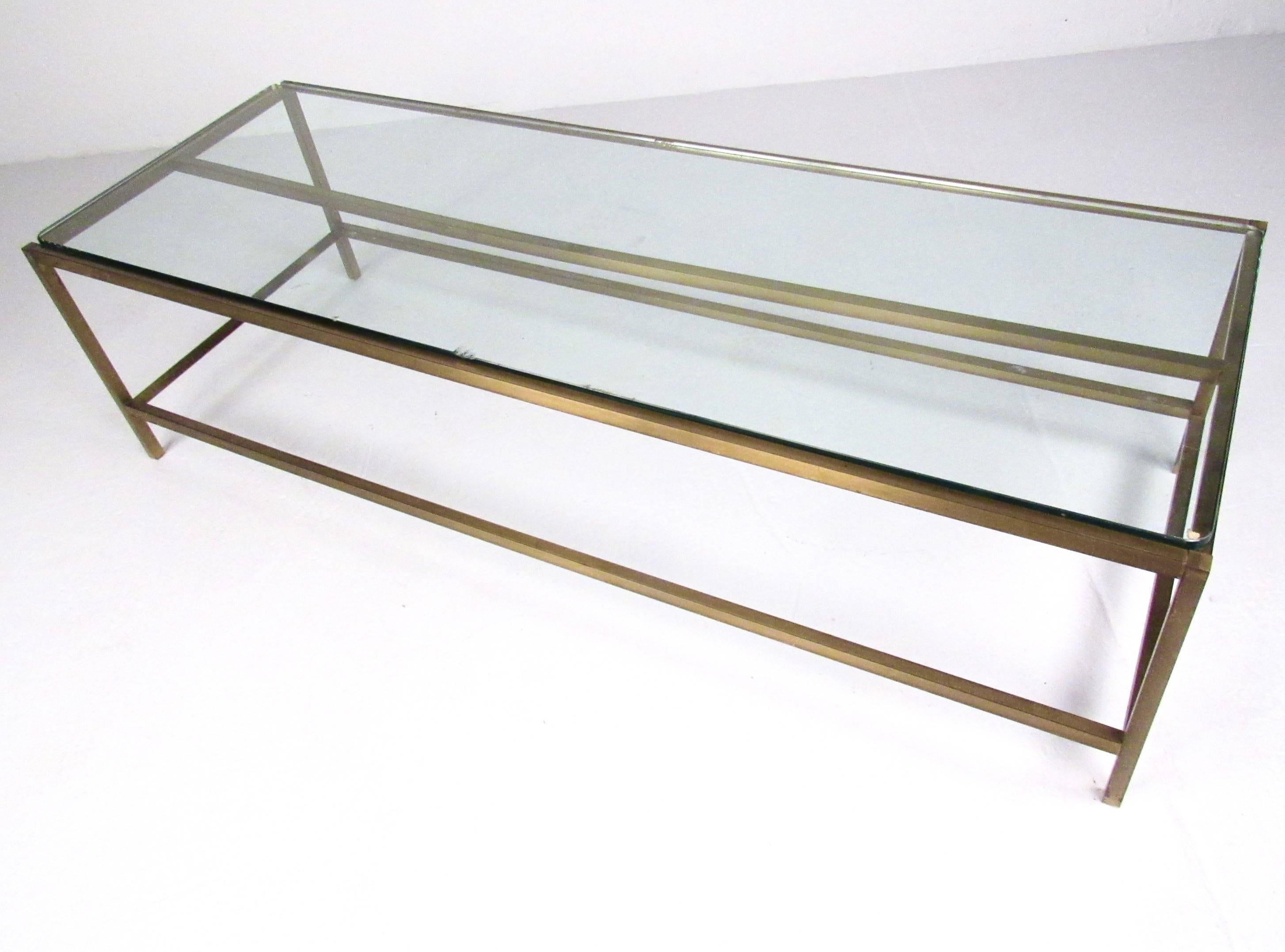 This impressive brass frame coffee table features a large rectangular frame with a unique patinated finish. Sturdy Mid-Century coffee table ideal for large seating areas and featuring the vintage design style of Harvey Probber. Please confirm item