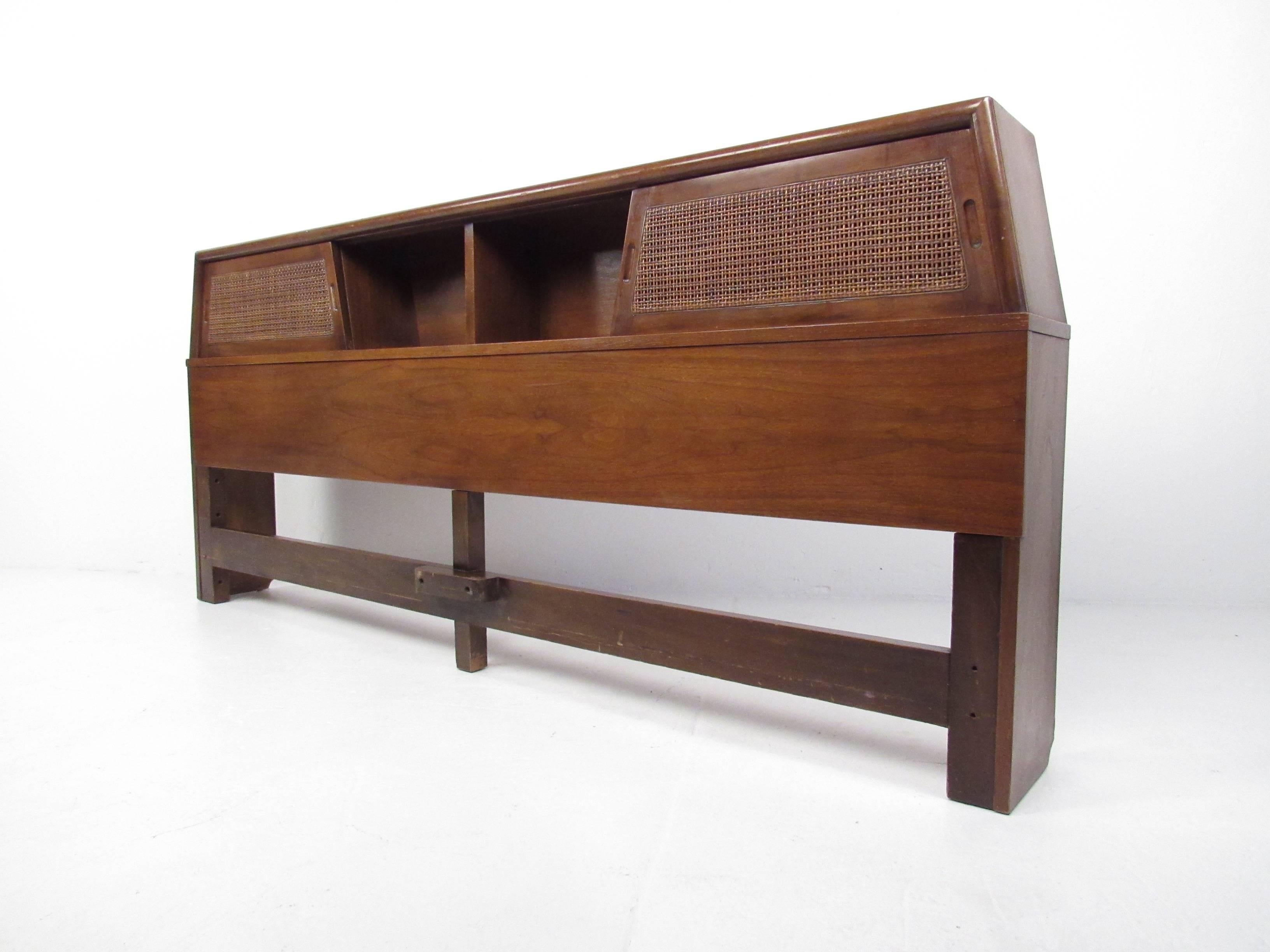 This vintage modern king-size headboard features sliding cane front cabinet doors offering concealed storage in a stylish package. Beautiful walnut finish adds to this well constructed Mid-Century headboard. Please confirm item location (NY or NJ).