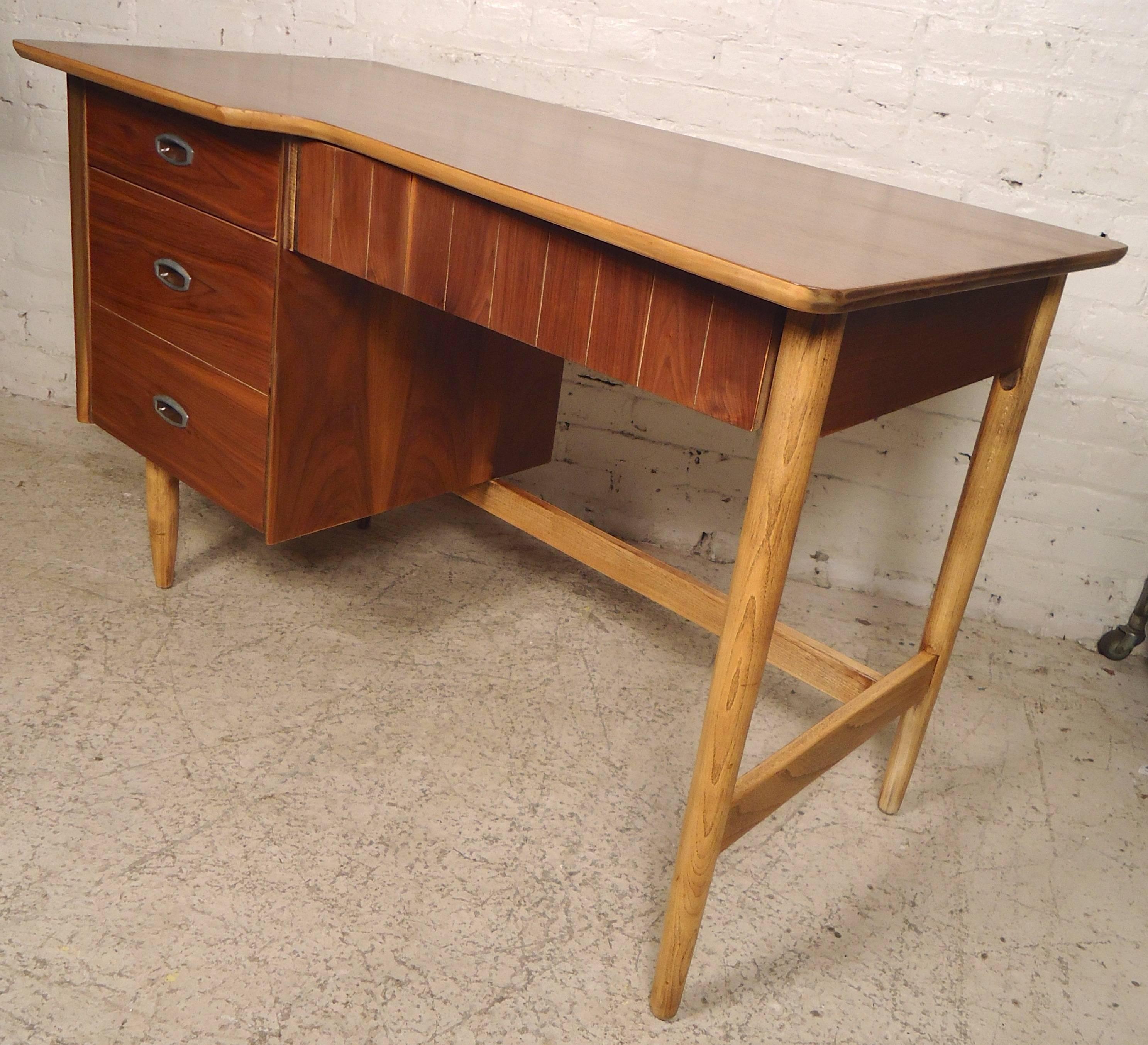 Vintage modern walnut desk with three drawers and kidney style cut away top. Attractive blonde legs accent the warm walnut grain. Finished back allows for mid-room placement.
Kneehole measures: 24