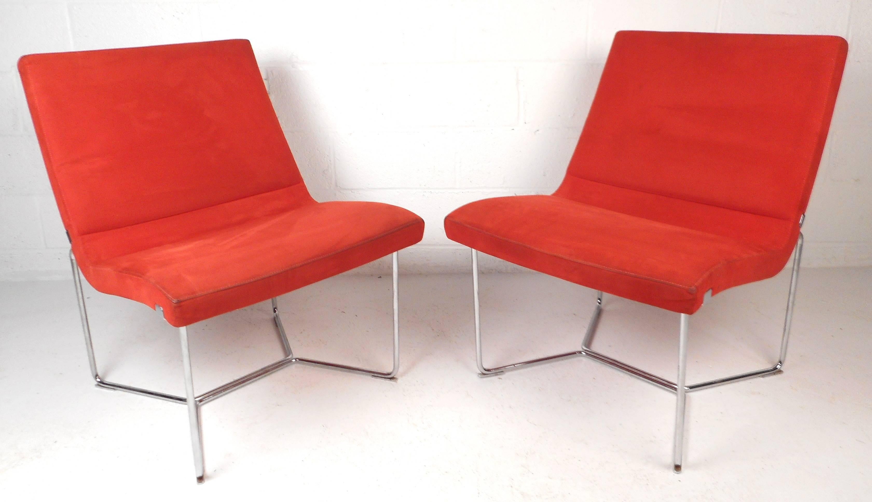 Stunning pair of mid-century modern slipper lounge chairs feature plush bright red velvet upholstery and a tubular bent rod chrome base. The sleek design from Harter Furniture, out of Michigan, provides comfortable seating and certainly adds