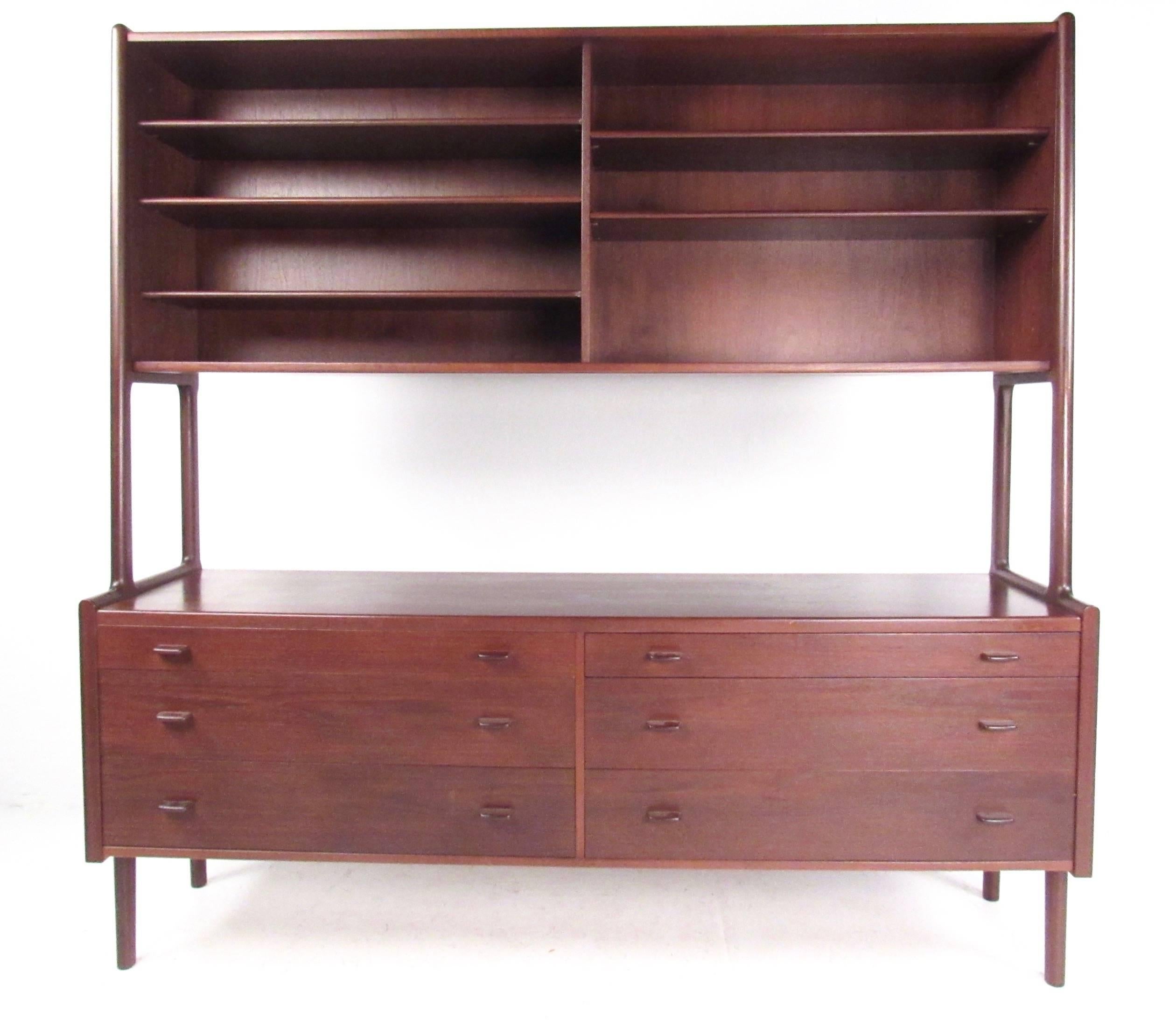 This vintage modern two-tier sideboard by Hans Wegner features a rich teak finish with carved wooden handles. This impressive Mid-Century sideboard combines open storage with graduated drawers for concealed storage. Top cabinet features sliding