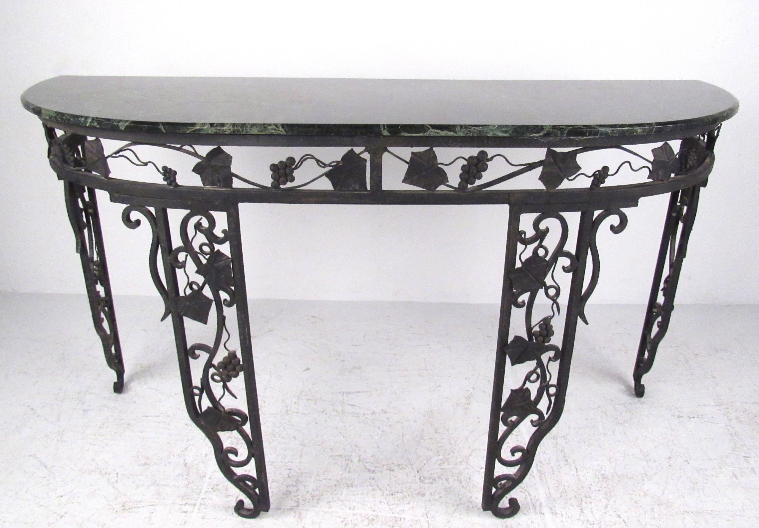 This ornate vintage demilune table features a heavy iron base paired with a marble top. Scrolled iron with vine and leaf motif add to the impressive appearance of the piece, making an excellent display table for hall or entryway. Two available,