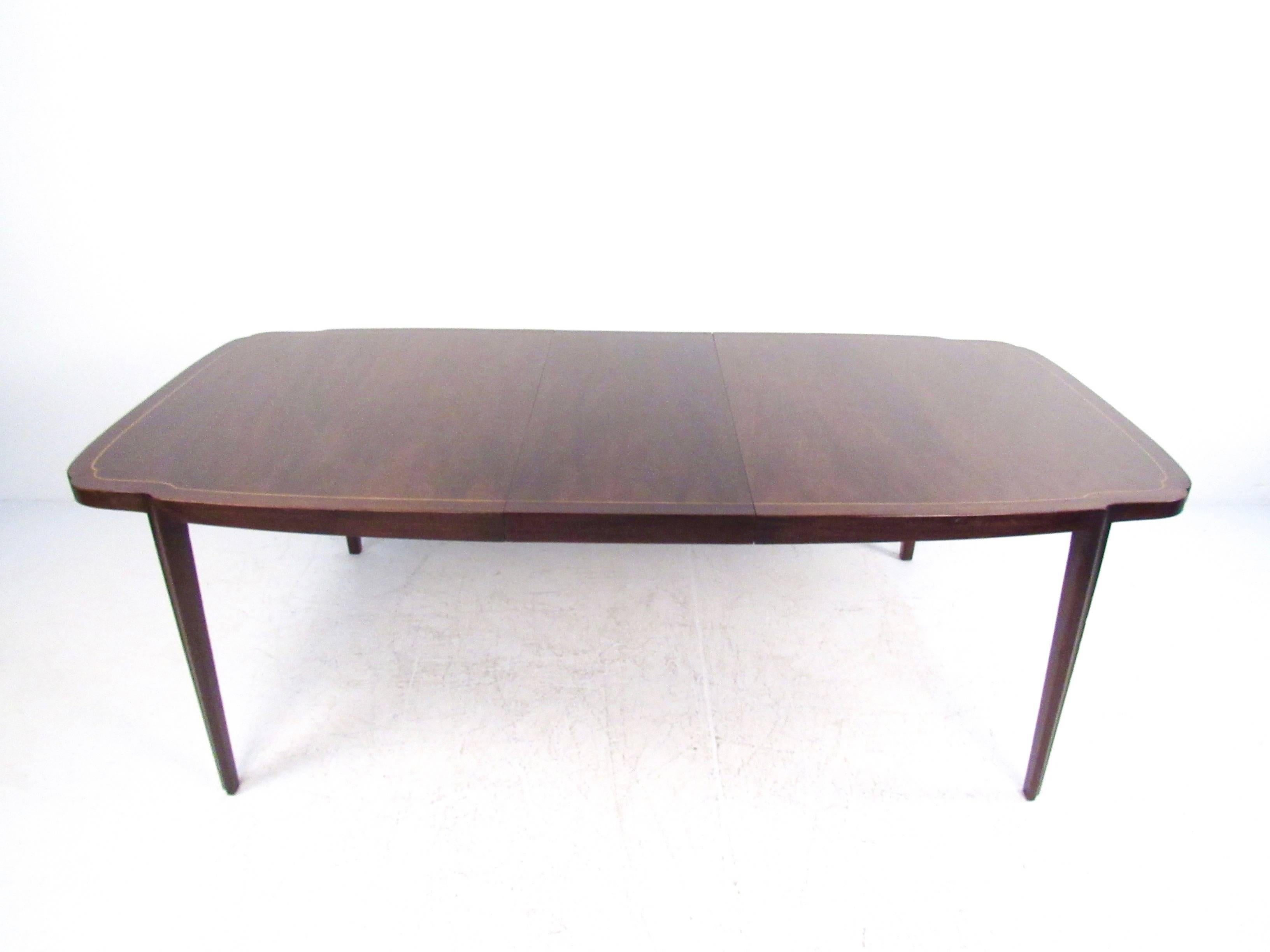 This exquisite lacquered dining table features uniquely shaped legs and an elegant cutaway tabletop complete with inlaid trim. Three eighteen inch leaves allow for this beautiful seventy-two inch table to expand to one hundred and twenty six inches