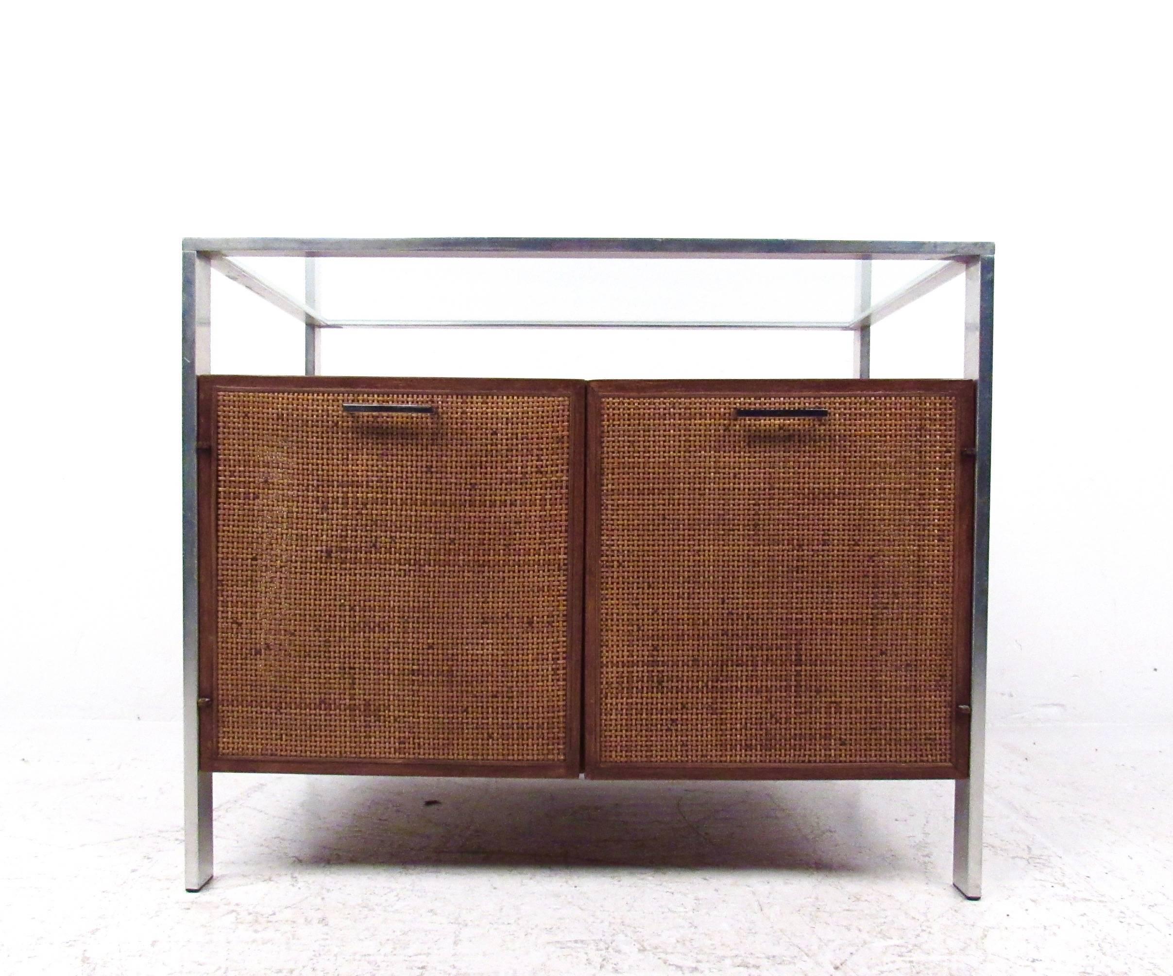 This vintage modern glass top cabinet features woven cane doors and sides with a two-tier top. Chrome finish frame and handles complete the unique Mid-Century Modern appeal of the piece. Perfect option for stylish home or office storage, please