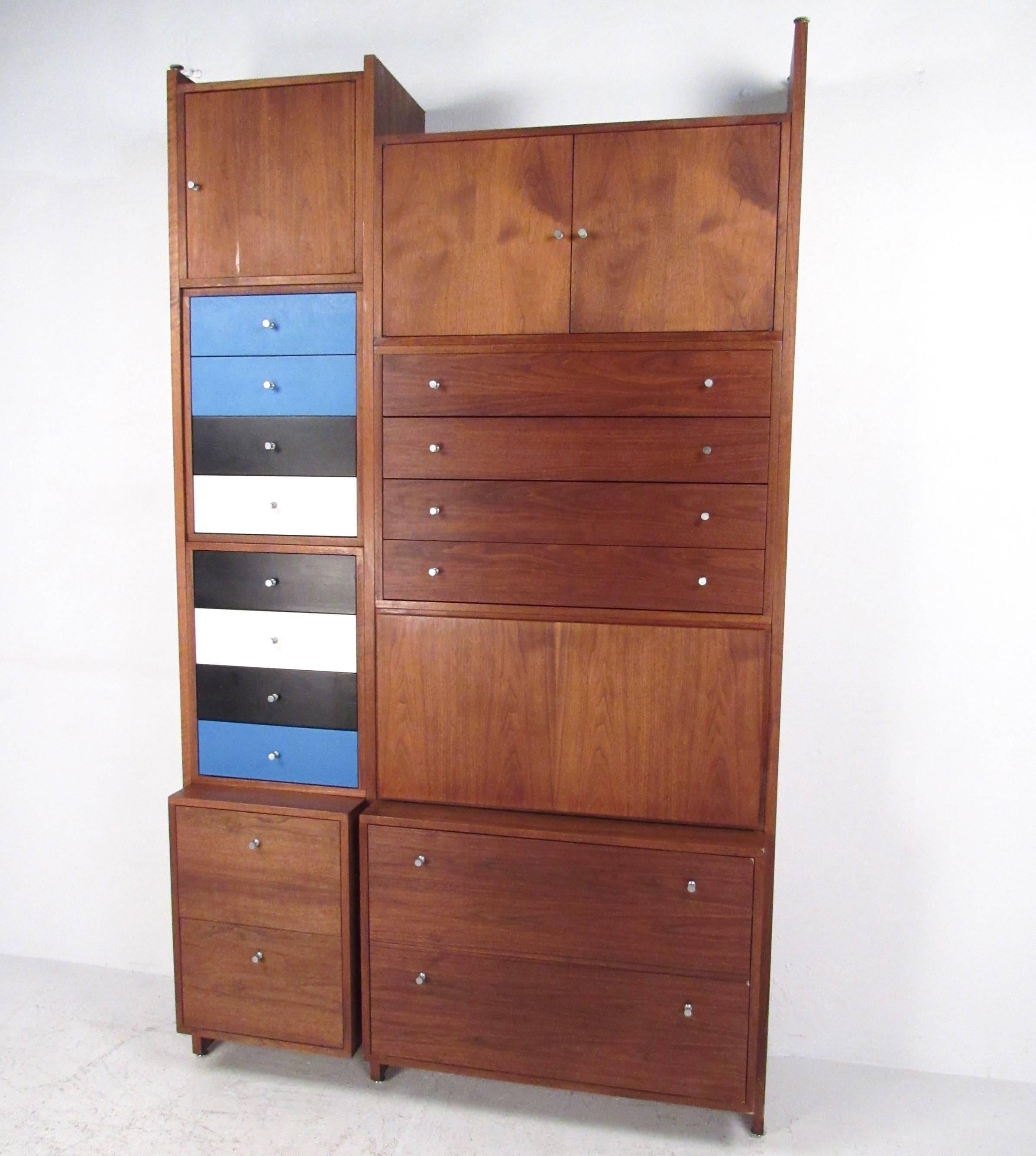This large modular wall cabinet features a stunning array of storage options in a uniquely designed package. Numerous drawers and cabinets are matched with a drop front writing desk, all within this impressive eight foot high cabinet. Rich walnut