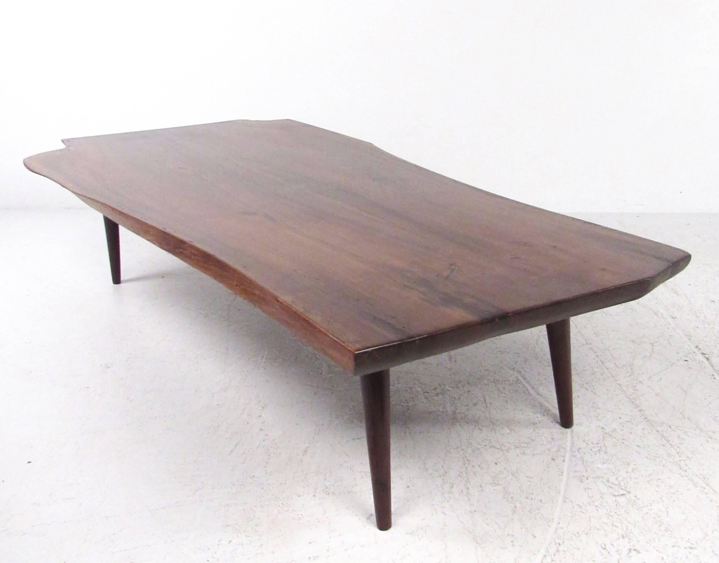 This vintage modern live edge coffee table features Nakashima style hardwood construction with tapered legs and bow tie joints. The high quality craftsmanship evident in this unique tree slab table make it an impressive centerpiece to any home or