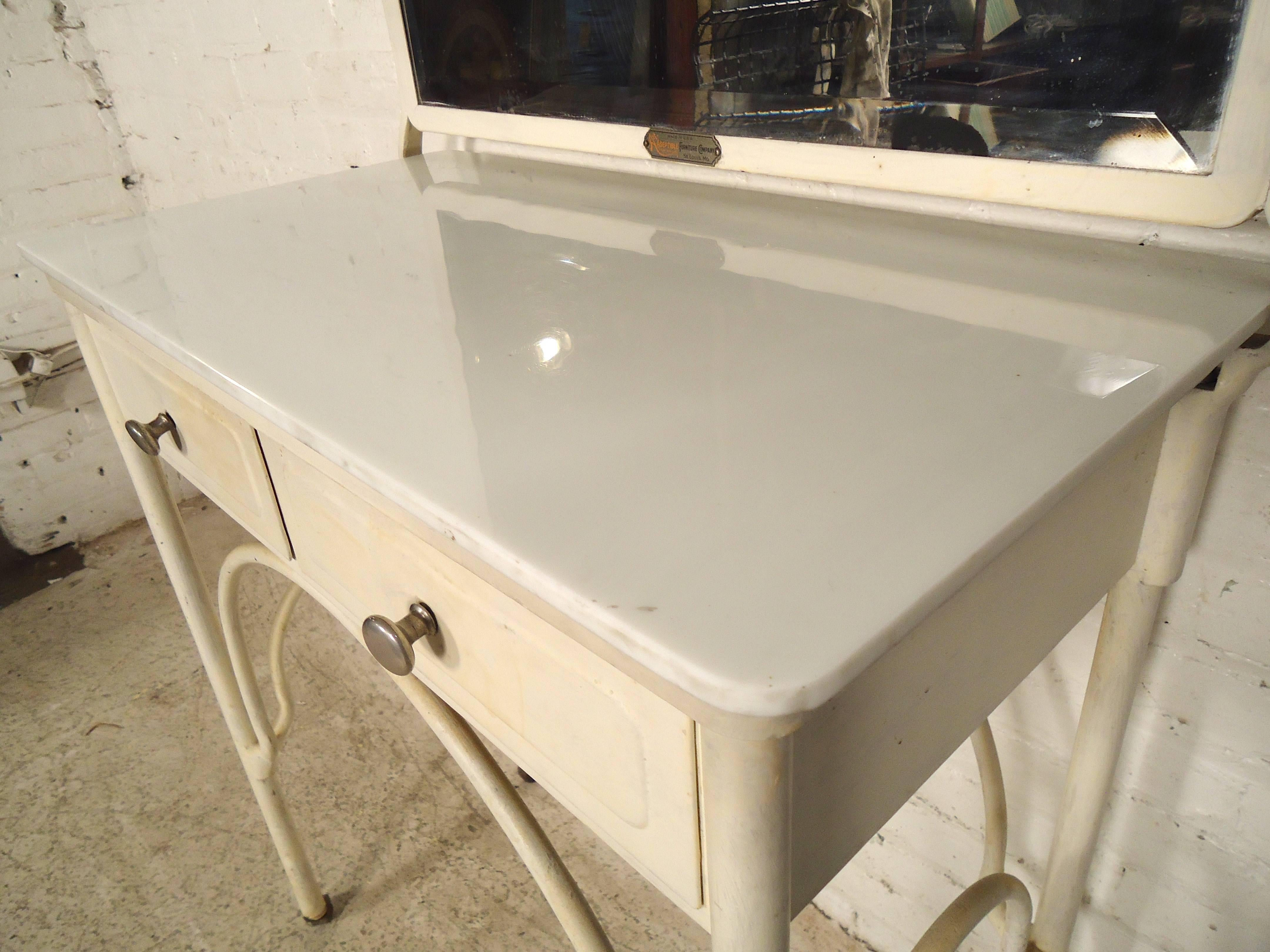 This unique vanity features white painted metal frame, large vintage mirror and a milk glass desk top. Rolling casters give easy mobility, and painted back allows for placement anywhere in the room.
This piece can also be stripped and given an