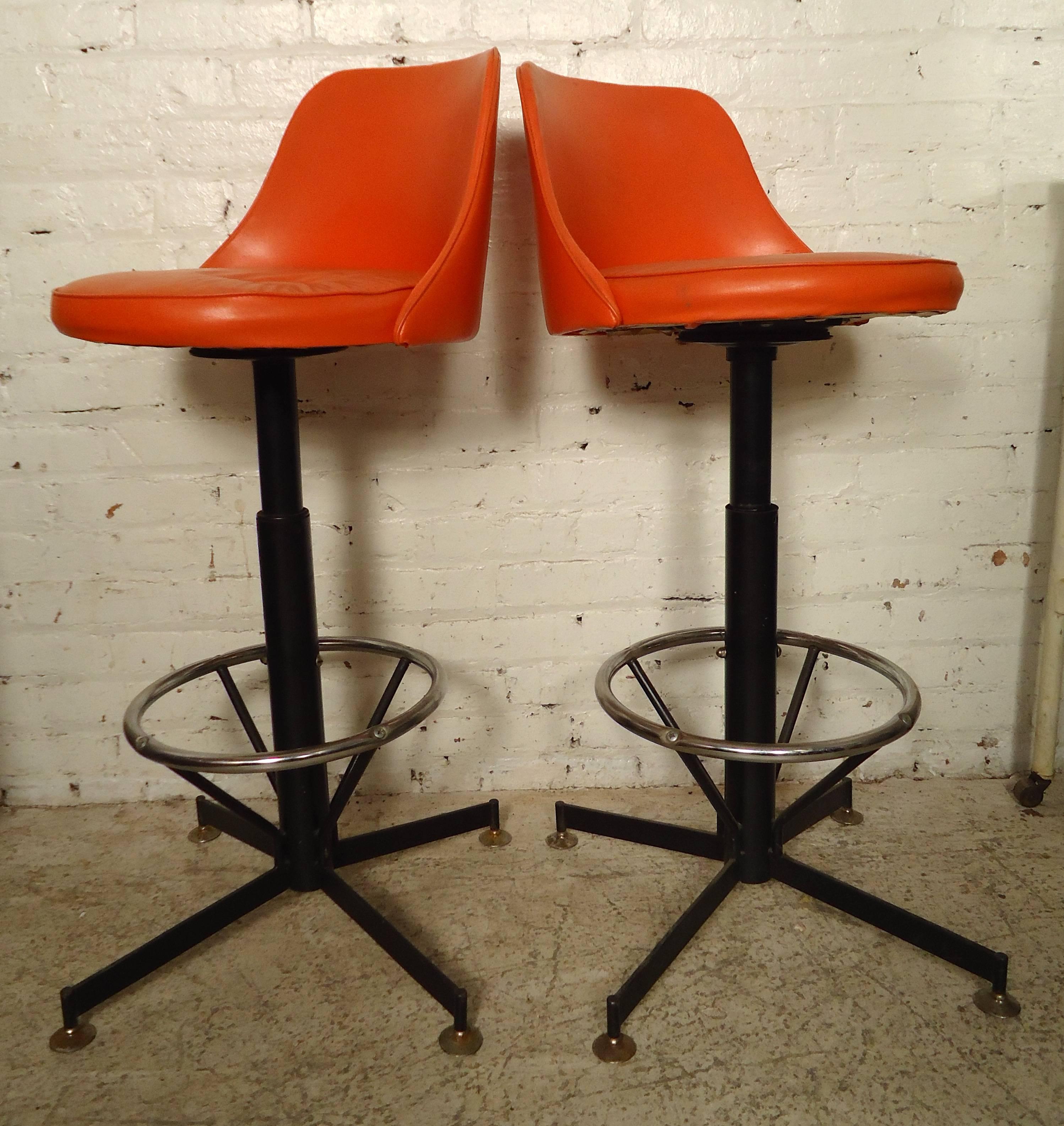 Pair of vintage modern swivel stools in orange vinyl with adjustable seat height set on a sturdy base.

Please confirm item location (NY or NJ) with dealer.