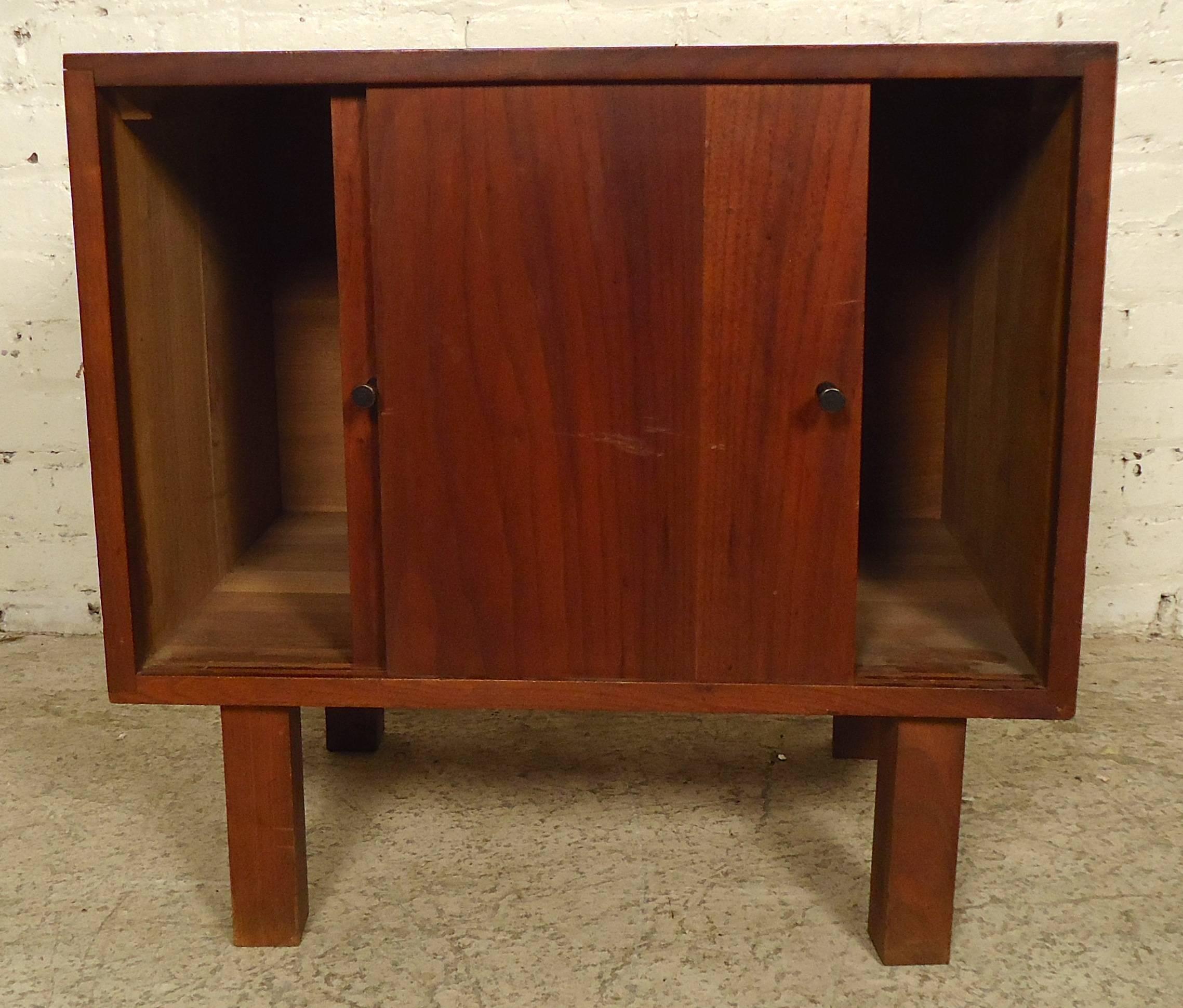 This vintage-modern side table features sliding doors, rich walnut grain and four solid legs.

Please confirm item location (NY or NJ) with dealer.
