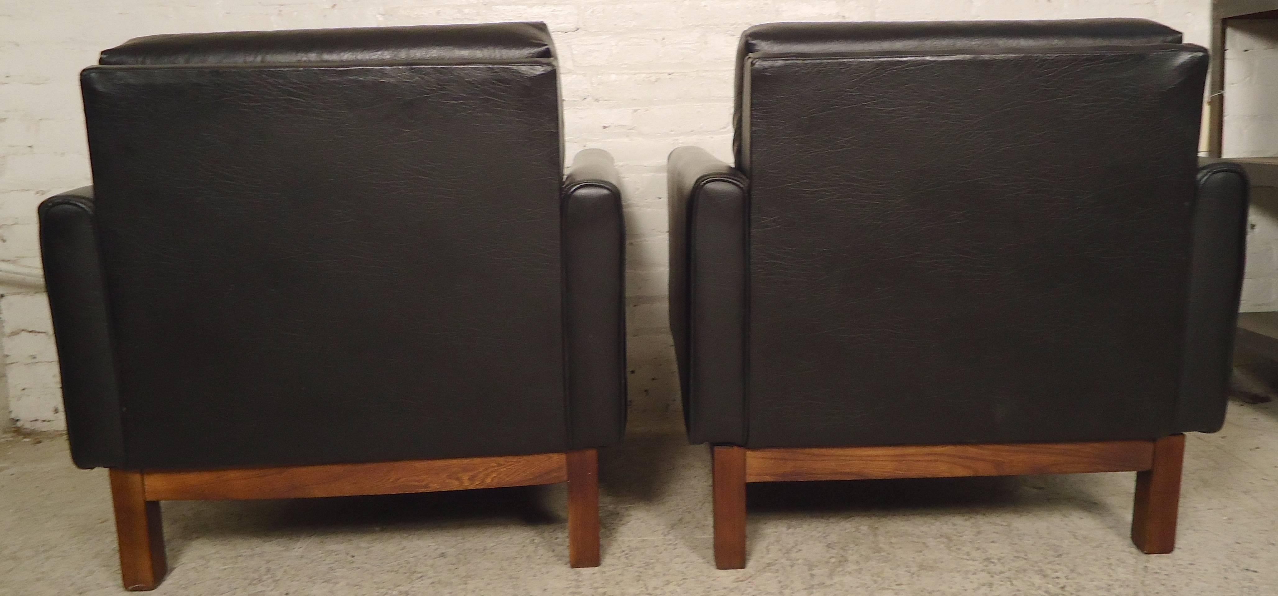 Classic black vinyl armchairs with simple lines and comfortable cushioning. Attractive teakwood frame adds to the handsome Mid-Century Modern feel.

(Please confirm item location NY or NJ with dealer).
 
