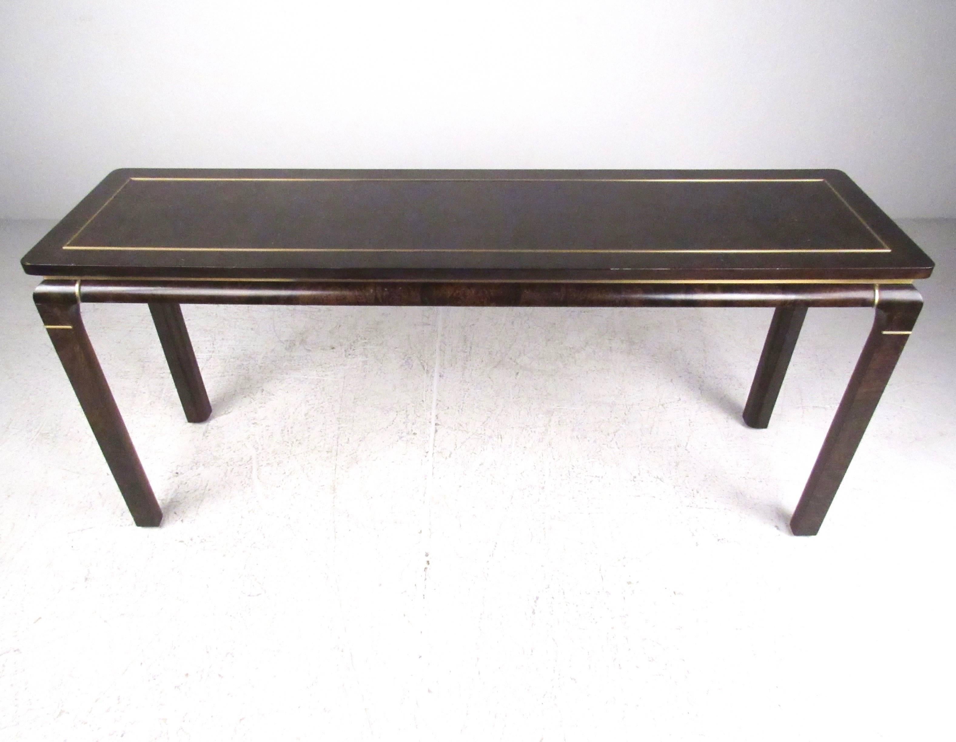 This vintage console table by John Stuart features a stylish Mid-Century design with dark burl lacquered finish and brass trim. Floating style tabletop accentuates the elegant appeal of this table, perfect for sofa or hall use. Please confirm item