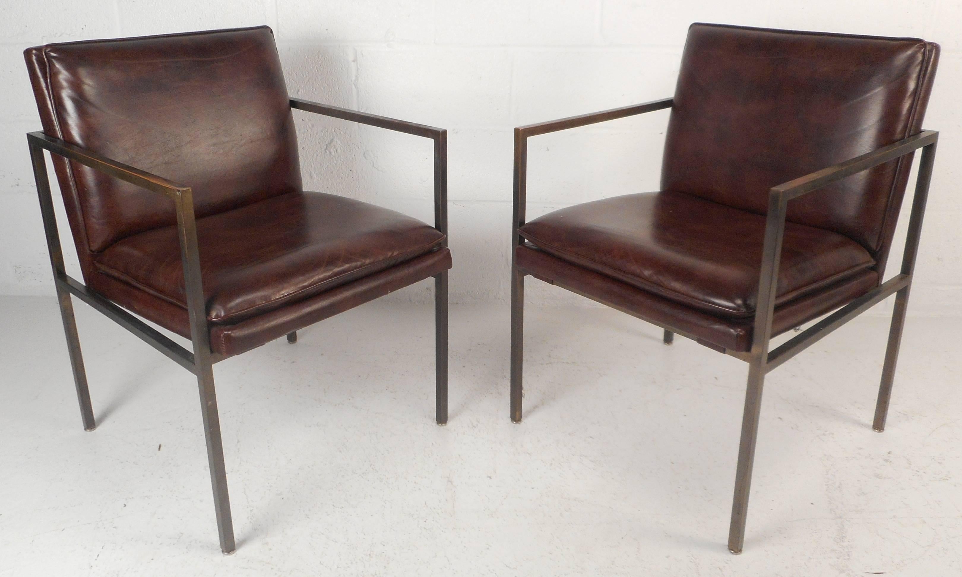 Elegant vintage modern pair of armchairs feature a solid brass frame with stylish brown vinyl upholstery. The unique design has thick padded seating with strategically placed armrests ensuring comfort. This Mid-Century pair shows quality