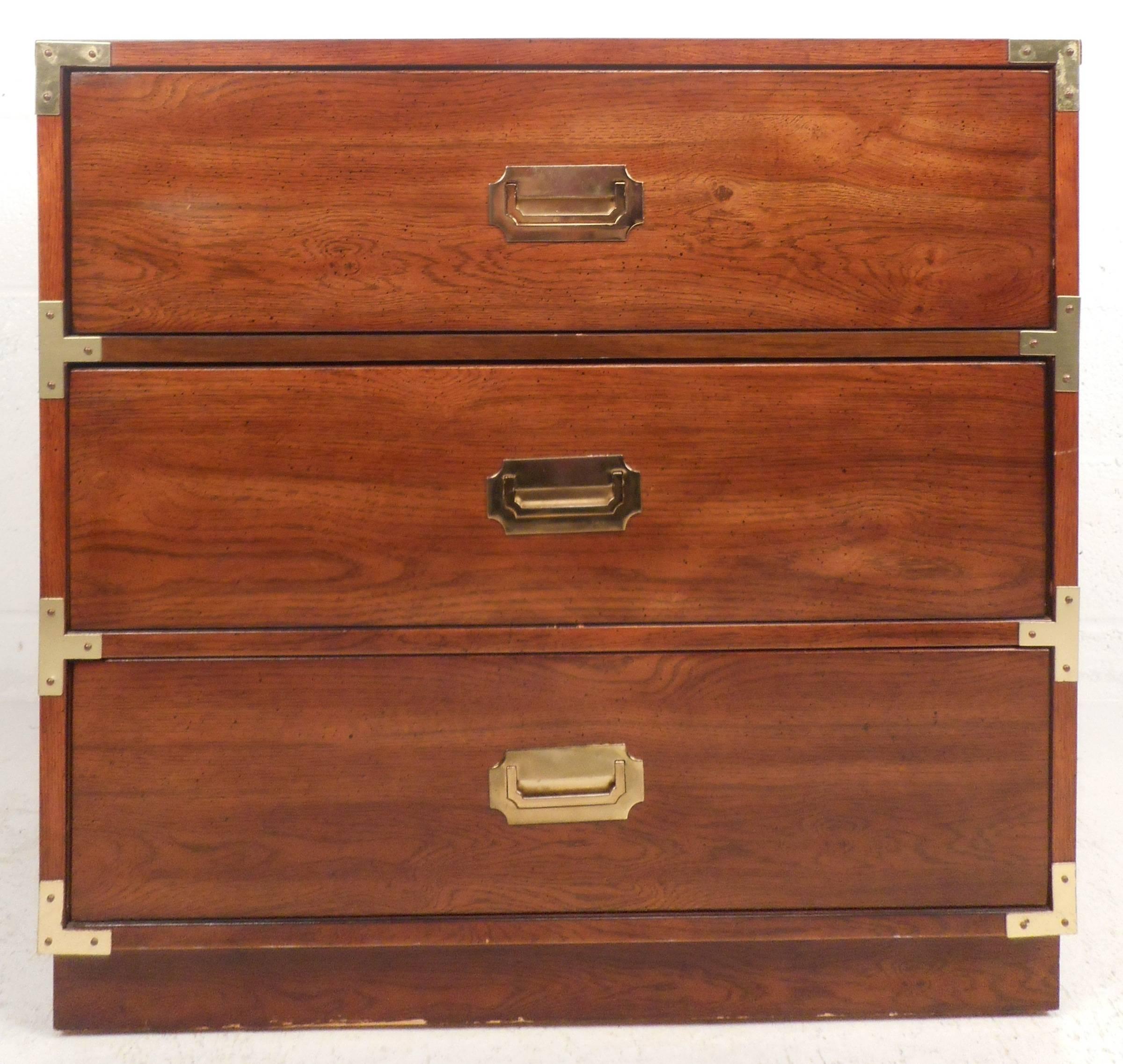 Stunning vintage modern Campaign style chest features three hefty drawers with unique brass pulls on each. The stylish brass detail on the corners of each drawer and the gorgeous walnut wood grain makes this Mid-Century piece the perfect addition to