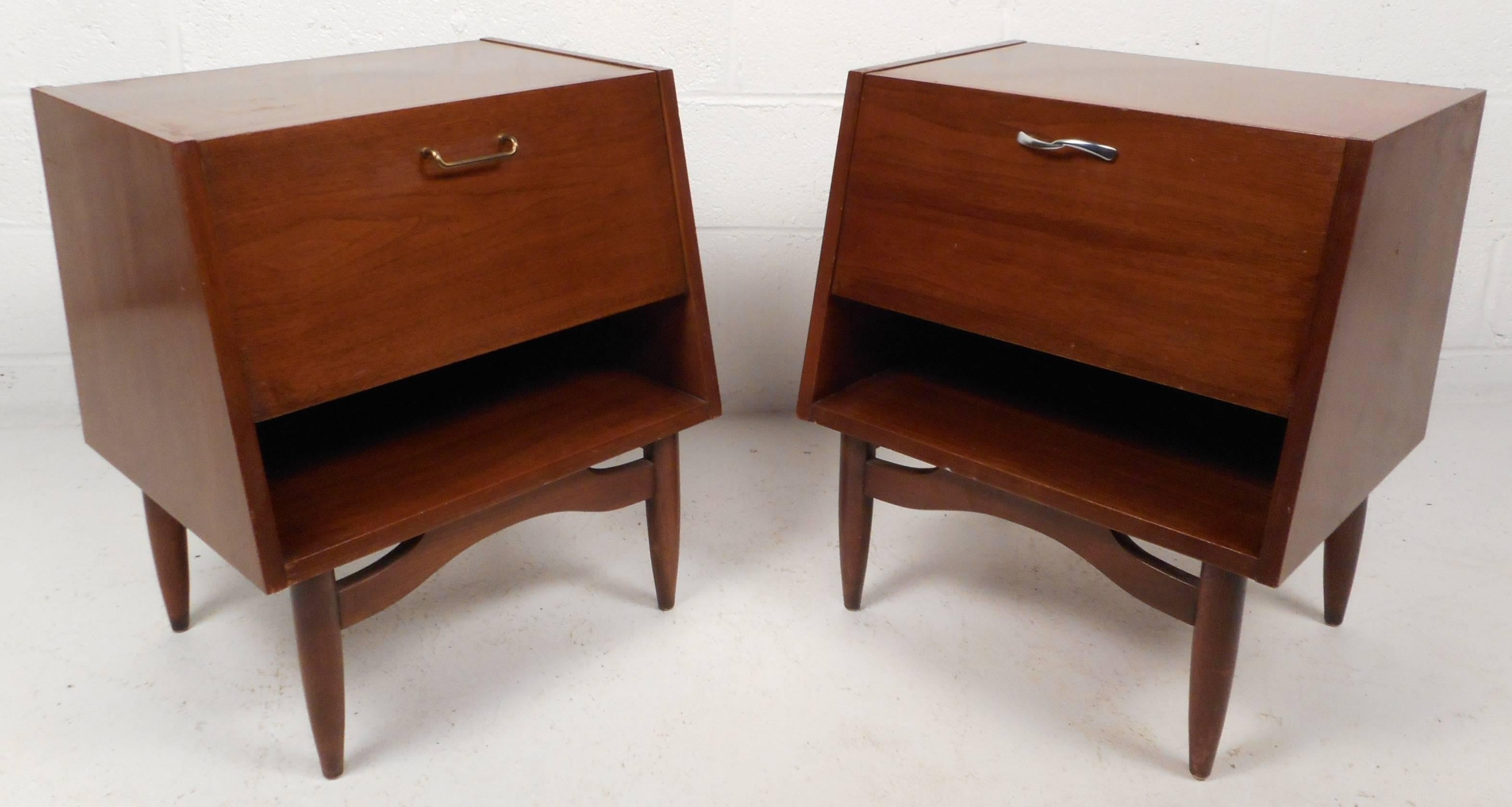 This beautiful pair of vintage modern walnut nightstands feature a drop front that displays a white laminate top when open. Unique design has a compartment and small drawer hidden behind the drop front. The stylish sculpted base and tapered legs add