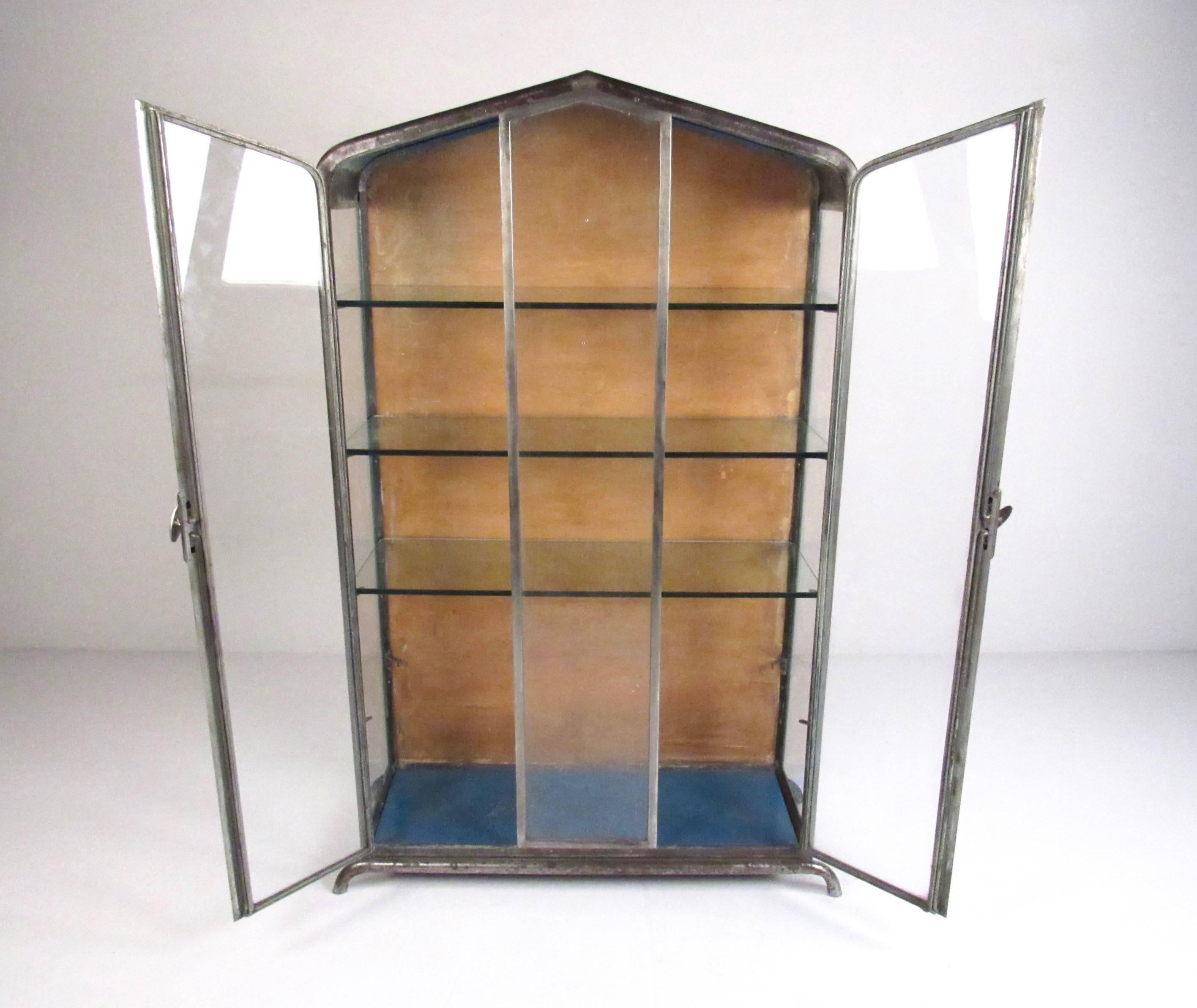 This unique deco style vitrine display case is constructed from Industrial metal with glass shelves and casing. Unique shape offers plenty of visibility making this the perfect piece for home or business display. Please confirm item location (NY or