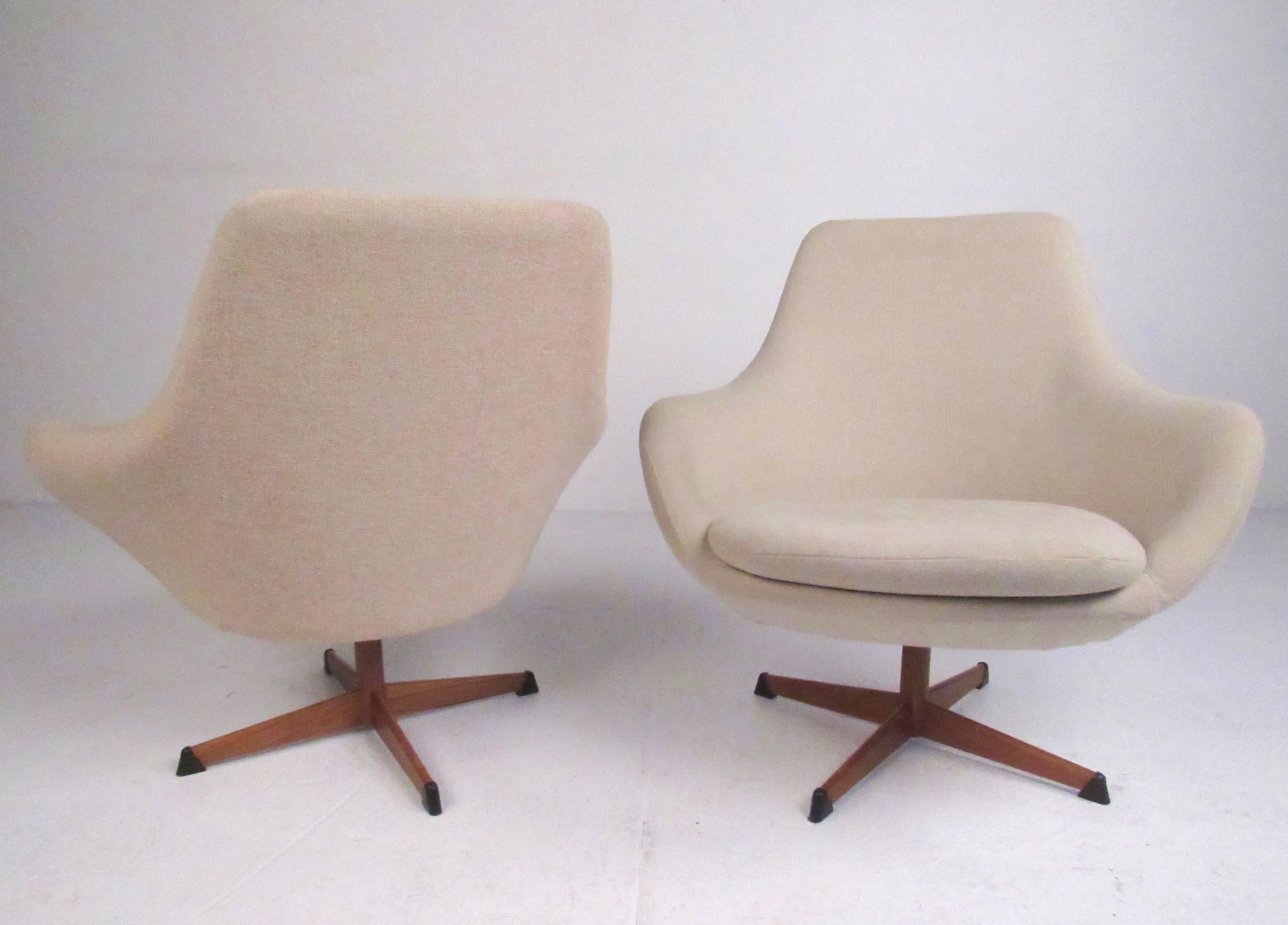 This stylish pair of swivel lounge chairs by Dahlens Dalum of Sweden make a beautiful Mid-Century addition to any interior. Sculpted seat backs and arms covered in vintage fabric mounted on a teak finish swivel base. Please confirm item location (NY