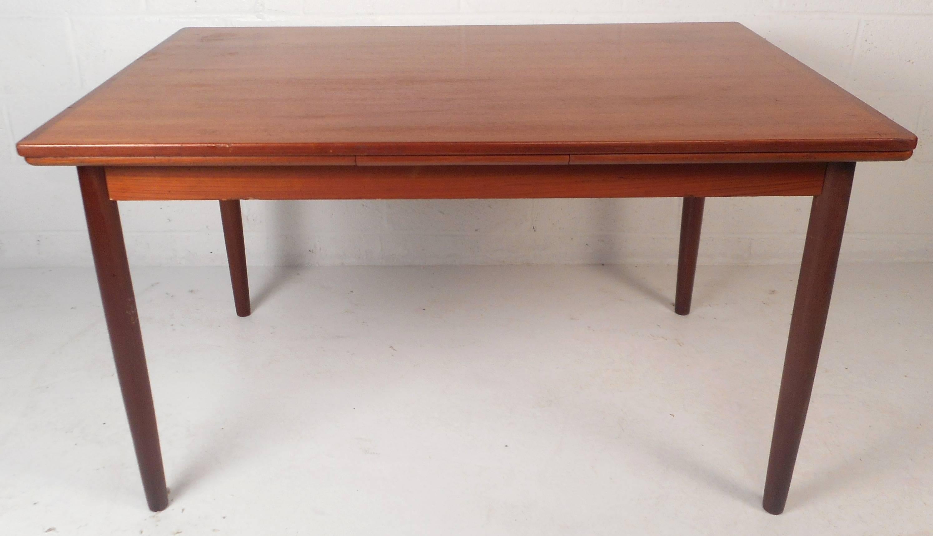 This beautiful vintage modern dining table features two hidden leaves that draw out to make this table an impressive 93.25" wide. Elegant teak wood grain and tapered legs add to the allure. This versatile design is sure to make a lasting