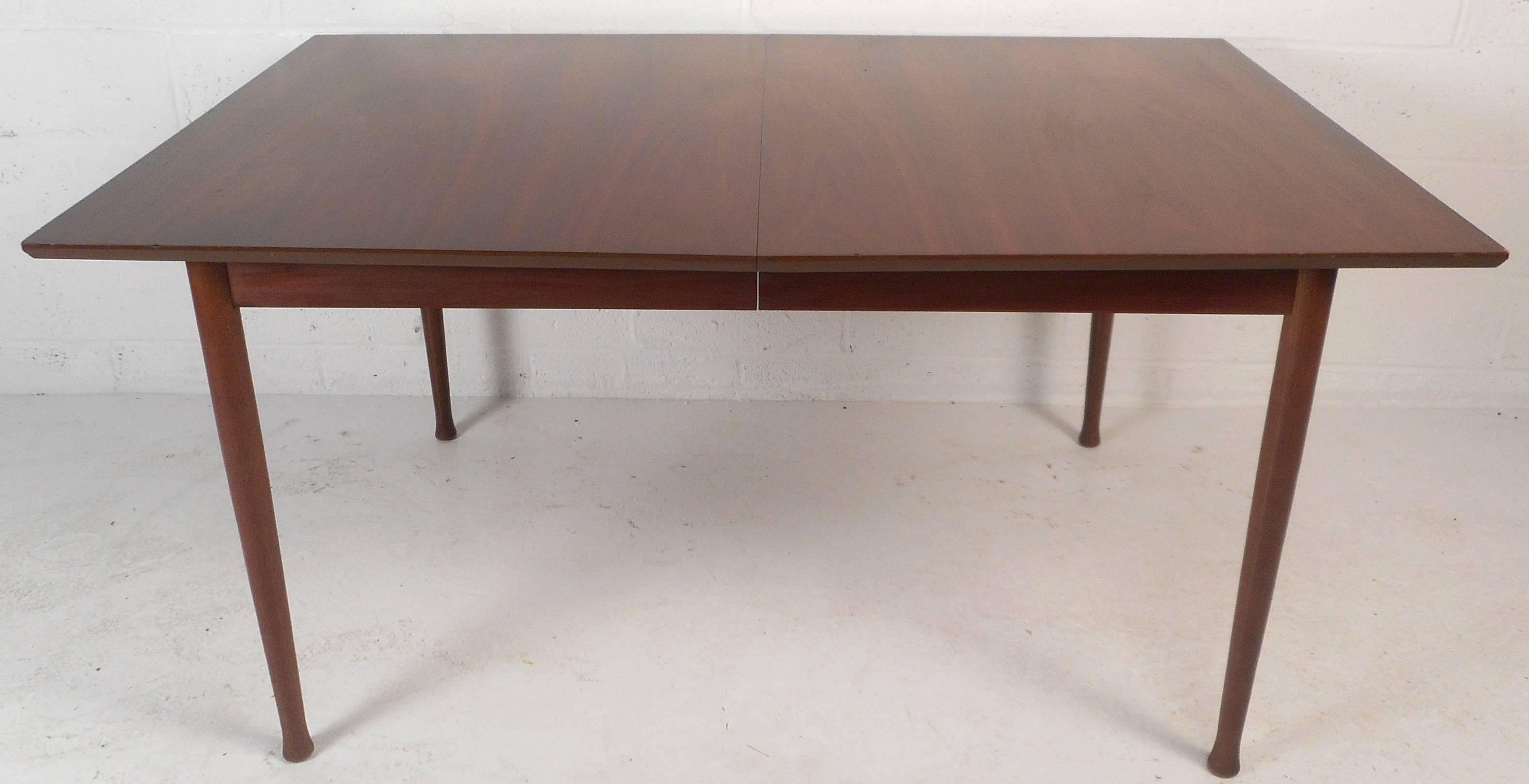 This beautiful vintage modern dining table has rosewood accents along the edges of two sides. Stylish design with unique drum stick legs and elegant wood grain. Sturdy construction with stunning features makes the perfect addition to any modern