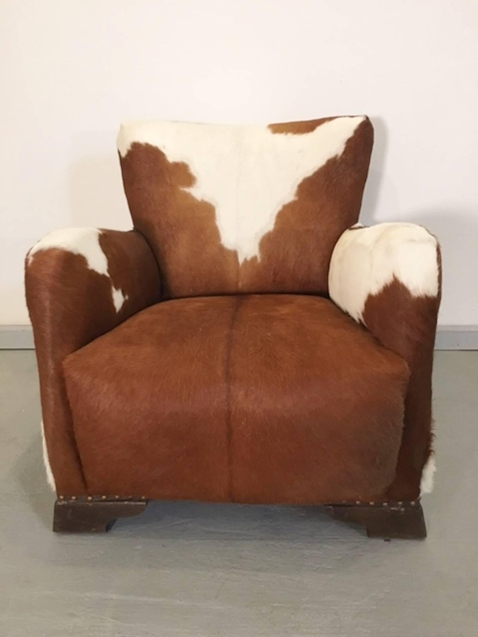 Handsome pair of vintage lounge chairs covered in superb brown and white cowhide. Wood feet with hammered nail trim.

(Please confirm item location with dealer).
             