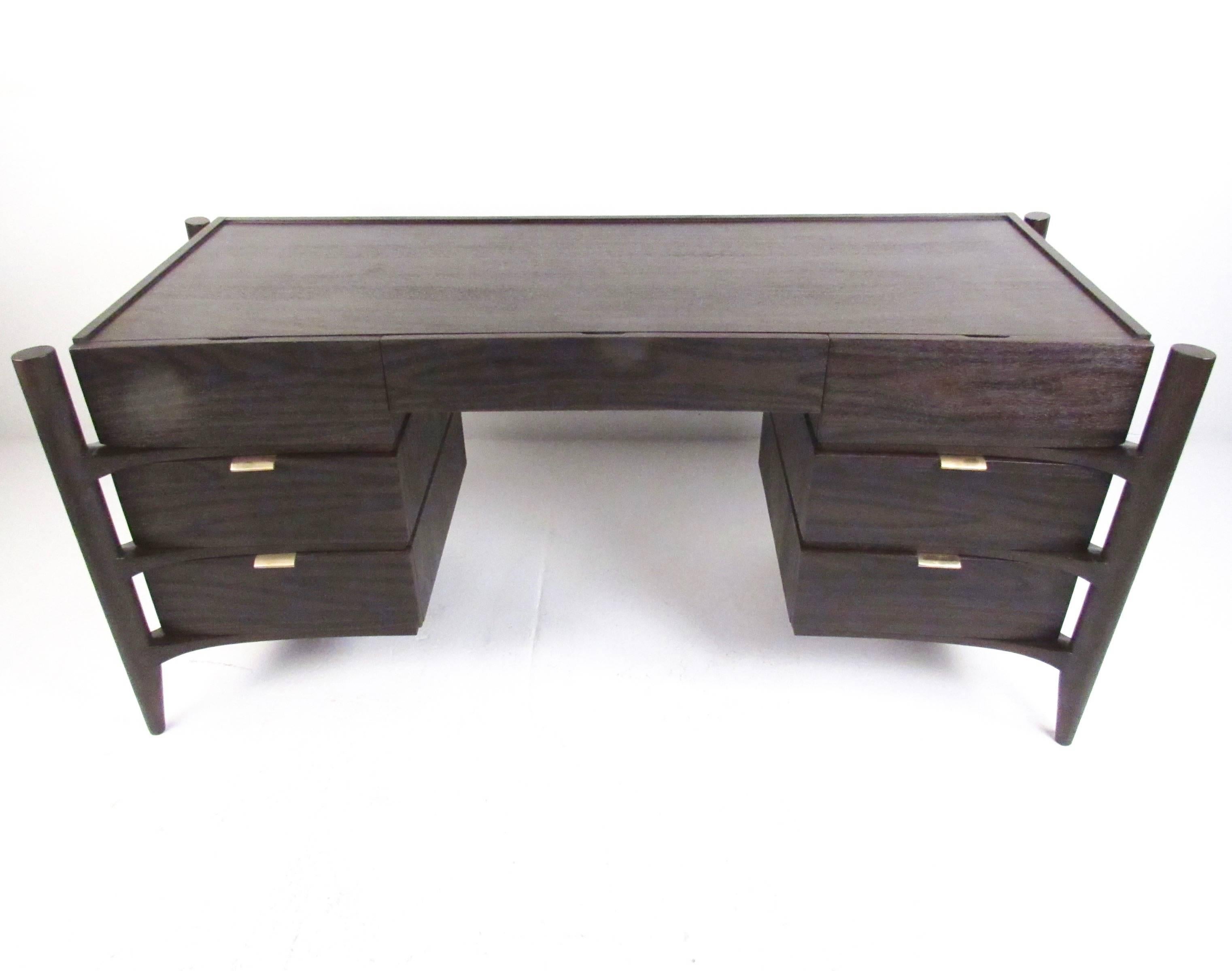 This stylish modern writing desk features unique sculpted design similar to the of Edmond Spence. The piece offers seven spacious drawers, striking wood grain finish; metal drawer pulls, and makes a beautiful addition to any home or office. Please