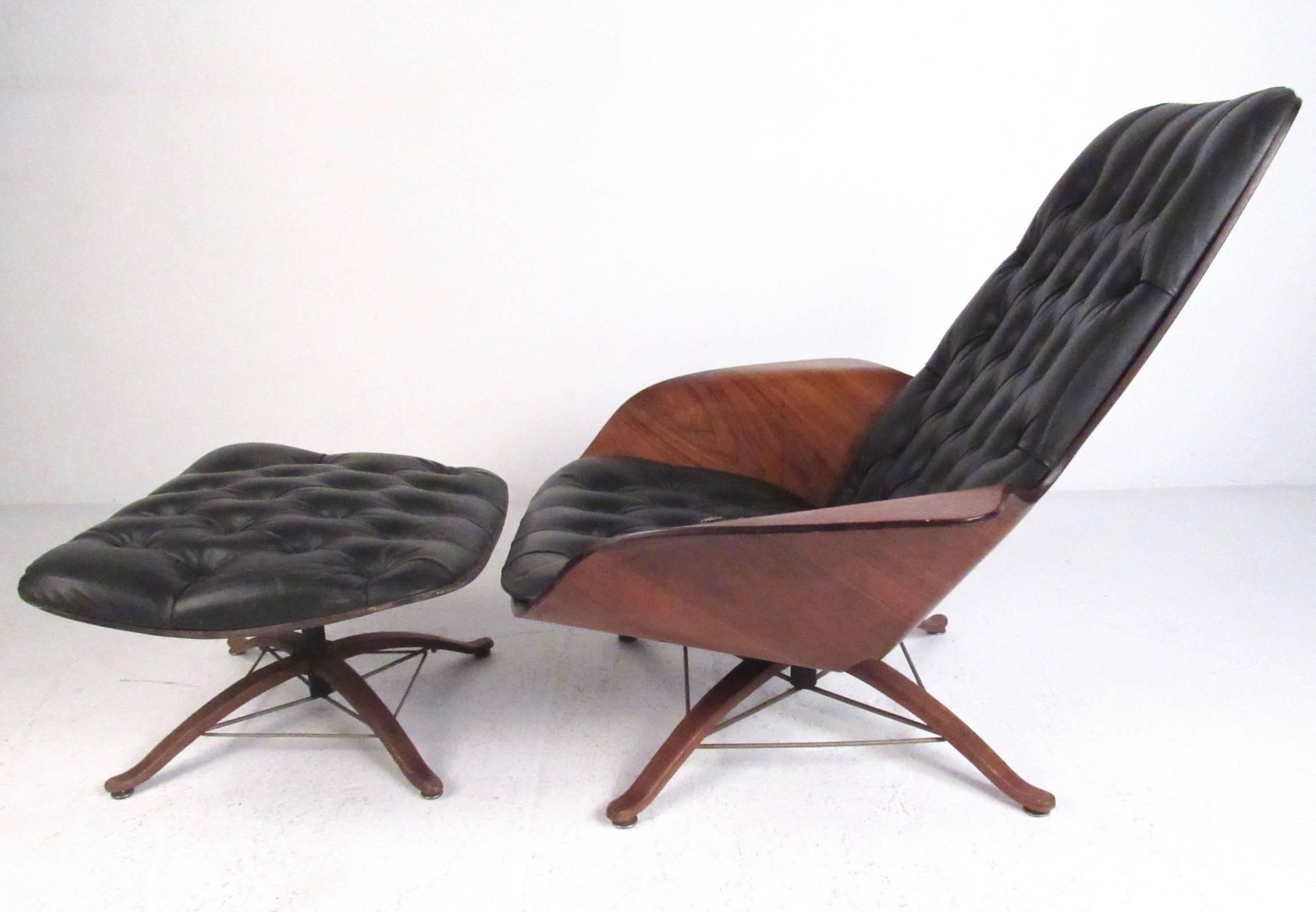 Cette chaise longue en contreplaqué moulé de George Mulhauser est dotée d'élégants accoudoirs en forme d'ailes, de vinyle touffeté et d'une base unique en bois dur avec des brancards en forme d'eiffel en laiton. La combinaison du design du milieu du