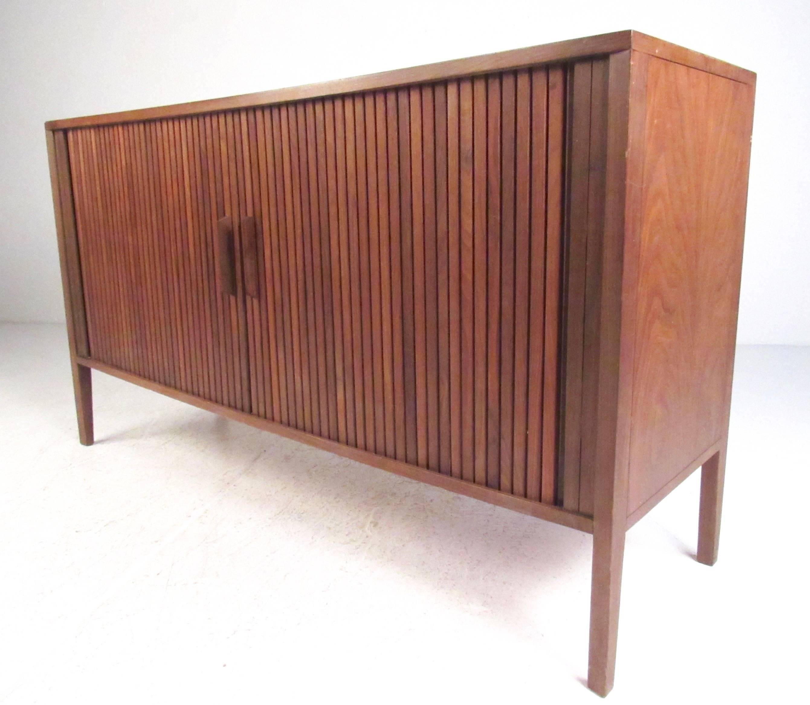 This stylish Mid-Century credenza makes a unique storage piece perfect for use as a television console, storage cabinet, or for occasional service. Walnut construction with tambour door and spacious shelf storage make this ideal for home or office.