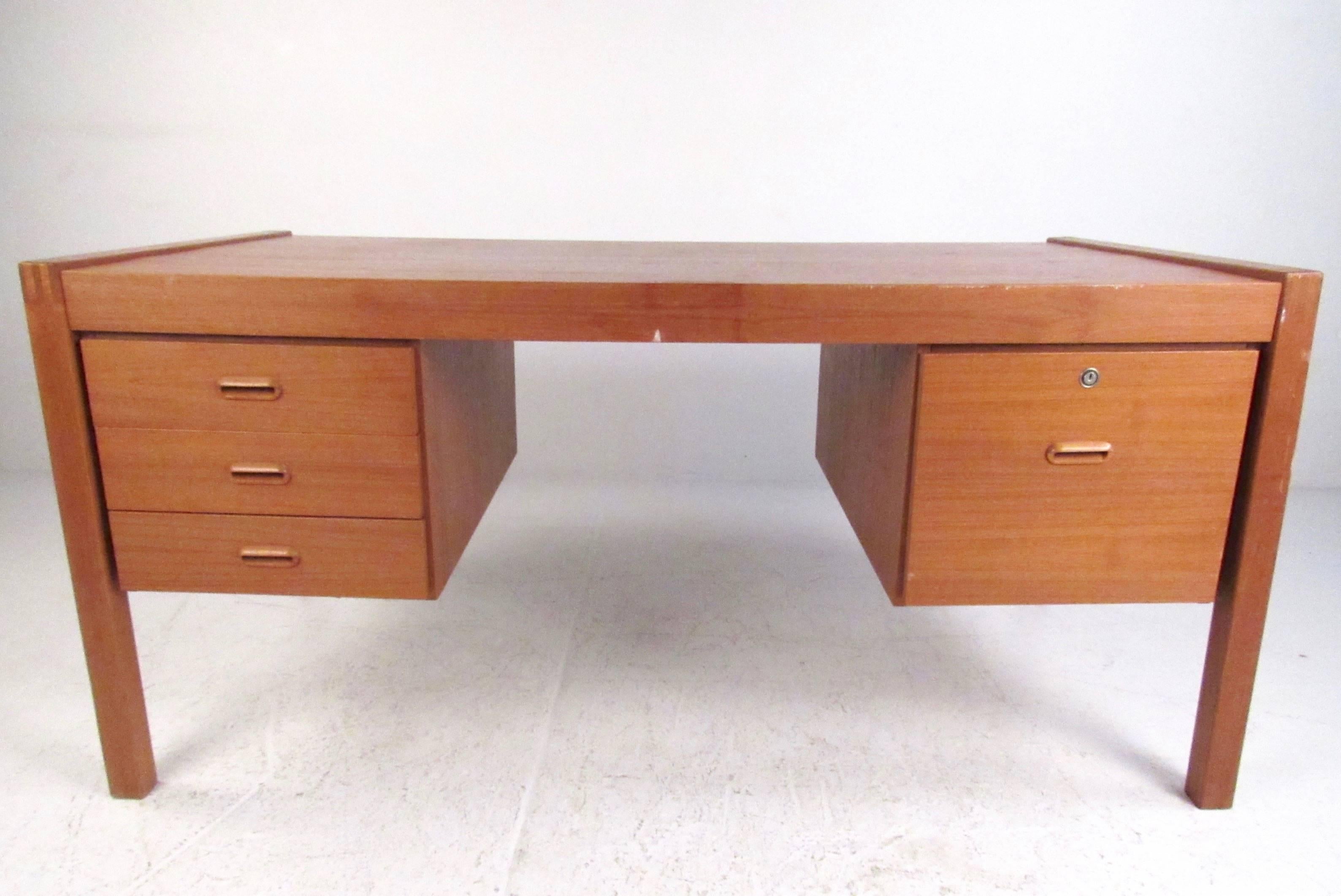 This stylish Scandinavian Modern desk features broad Danish design and teak finish. Dovetail details and carved drawer pulls add to the spacious storage offered within its four drawers. Please confirm item location (NY or NJ).