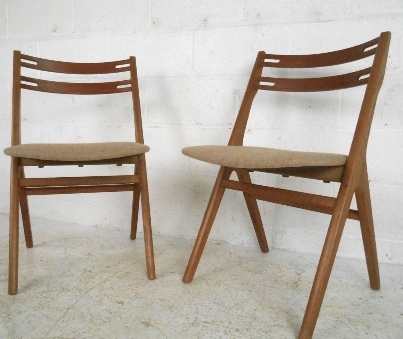 This matching pair of vintage modern dining chairs feature uniquely shaped seat backs, vintage upholstery, and sturdy, stylish construction. Perfect addition to any dining room or for occasional seating in any setting. Please confirm item location