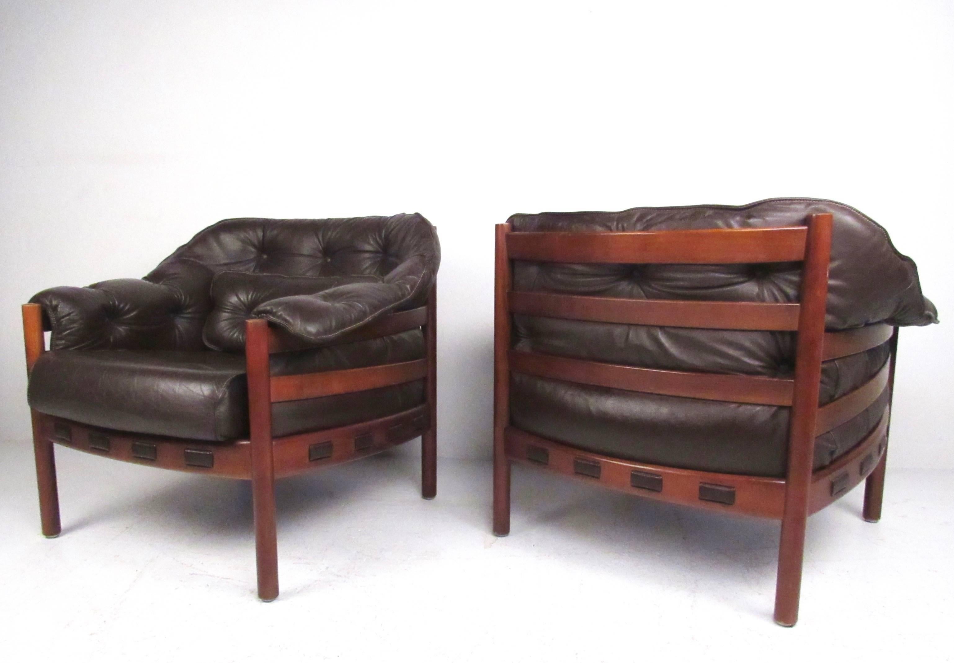 This tufted pair of Arne Norell club chairs feature rich brown leather upholstery with solid teak frames. Comfortable Mid-Century design for Coja Furniture make this matching tufted chairs an impressive addition to any interior. Please confirm item