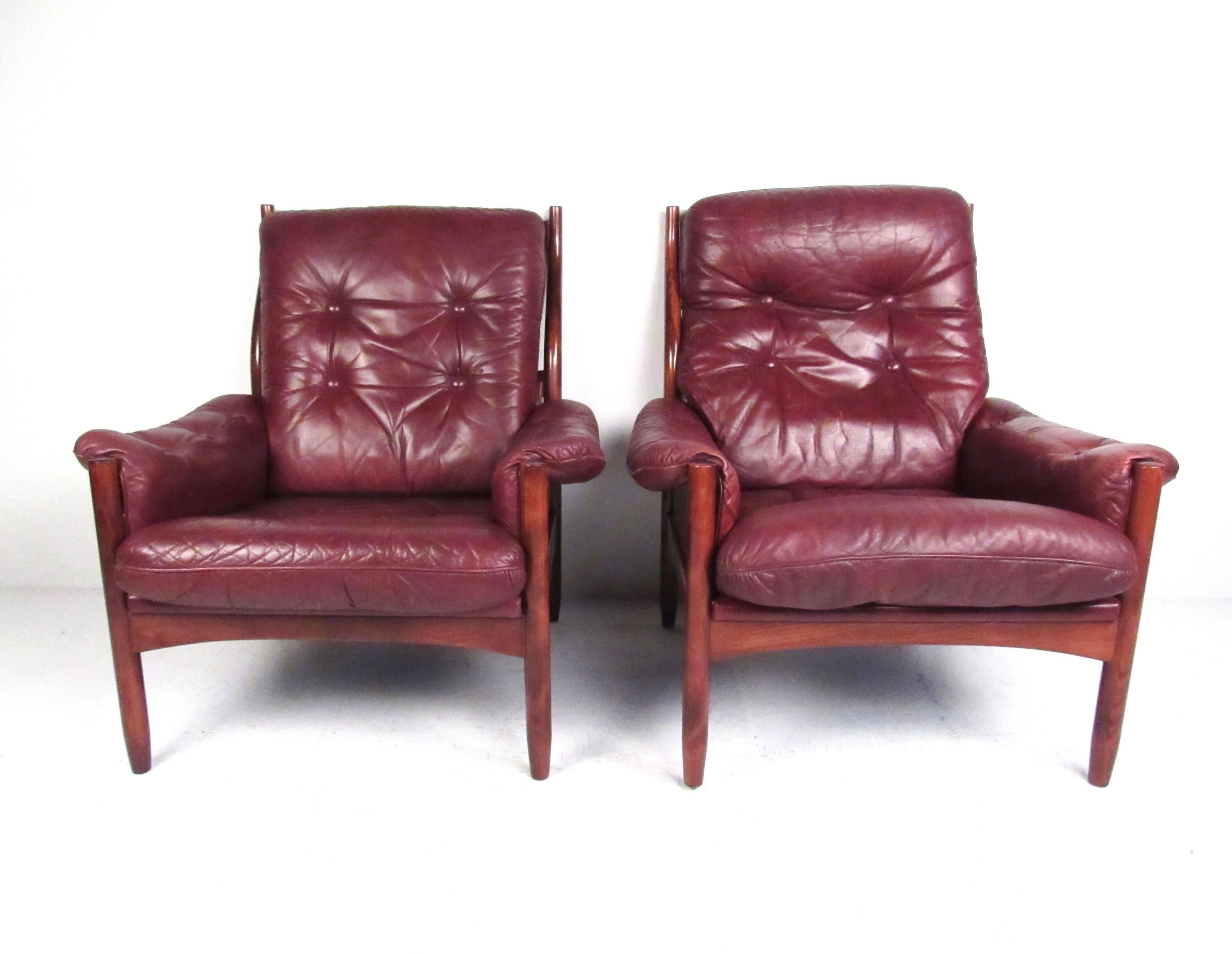 This beautiful pair Scandinavian Modern lounge chairs features tufted vintage leather, sleek and slender rosewood frame, and unique Danish design. The comfortable and stylish contour of the seat back adds to the mid-century appeal of the pair.