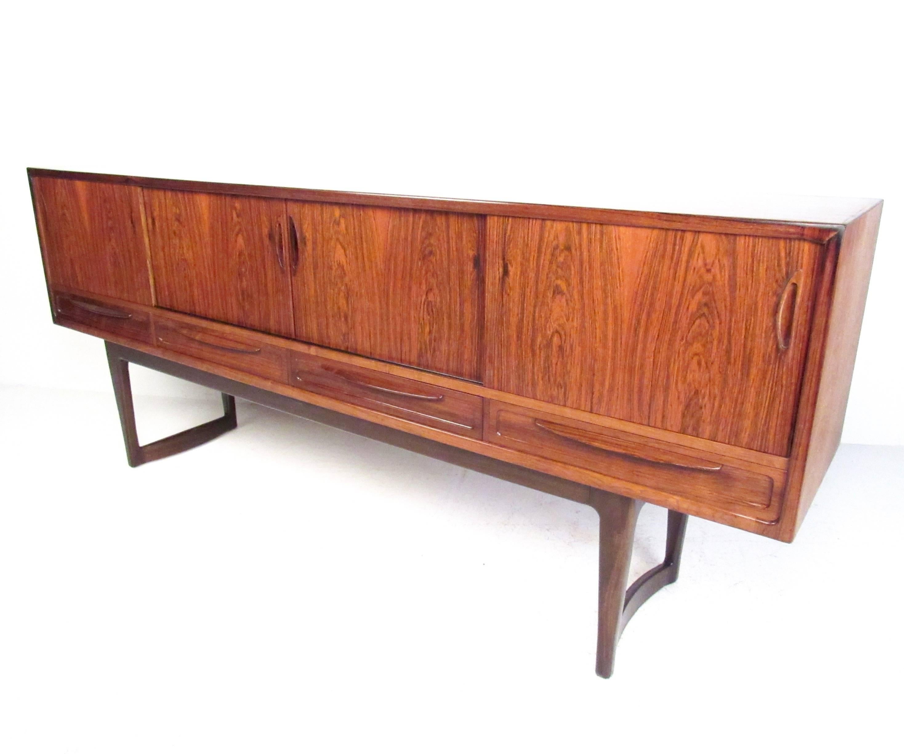 This gorgeous sled leg sideboard features stunning Mid-Century design, including sculpted handles, matched rosewood finish, and spacious storage. Felt-lined drawers and shelf storage cabinets make this the perfect piece for dining room, living room,
