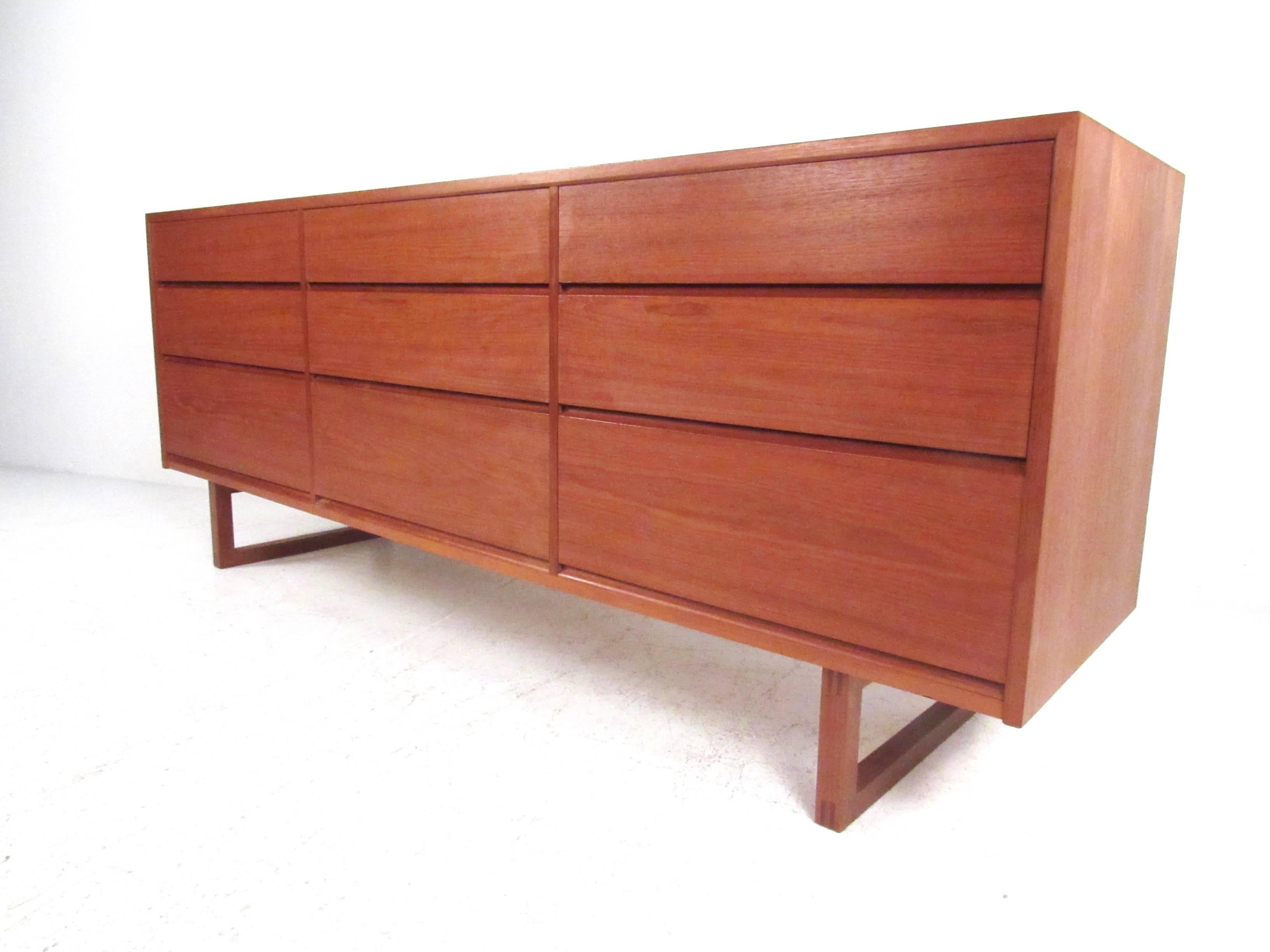 This vintage modern teak dresser features high quality Danish construction with dovetail drawers and stylish sled legs. Rich teak finish and nine spacious drawers for storage make this a versatile and visually impressive addition to any interior.