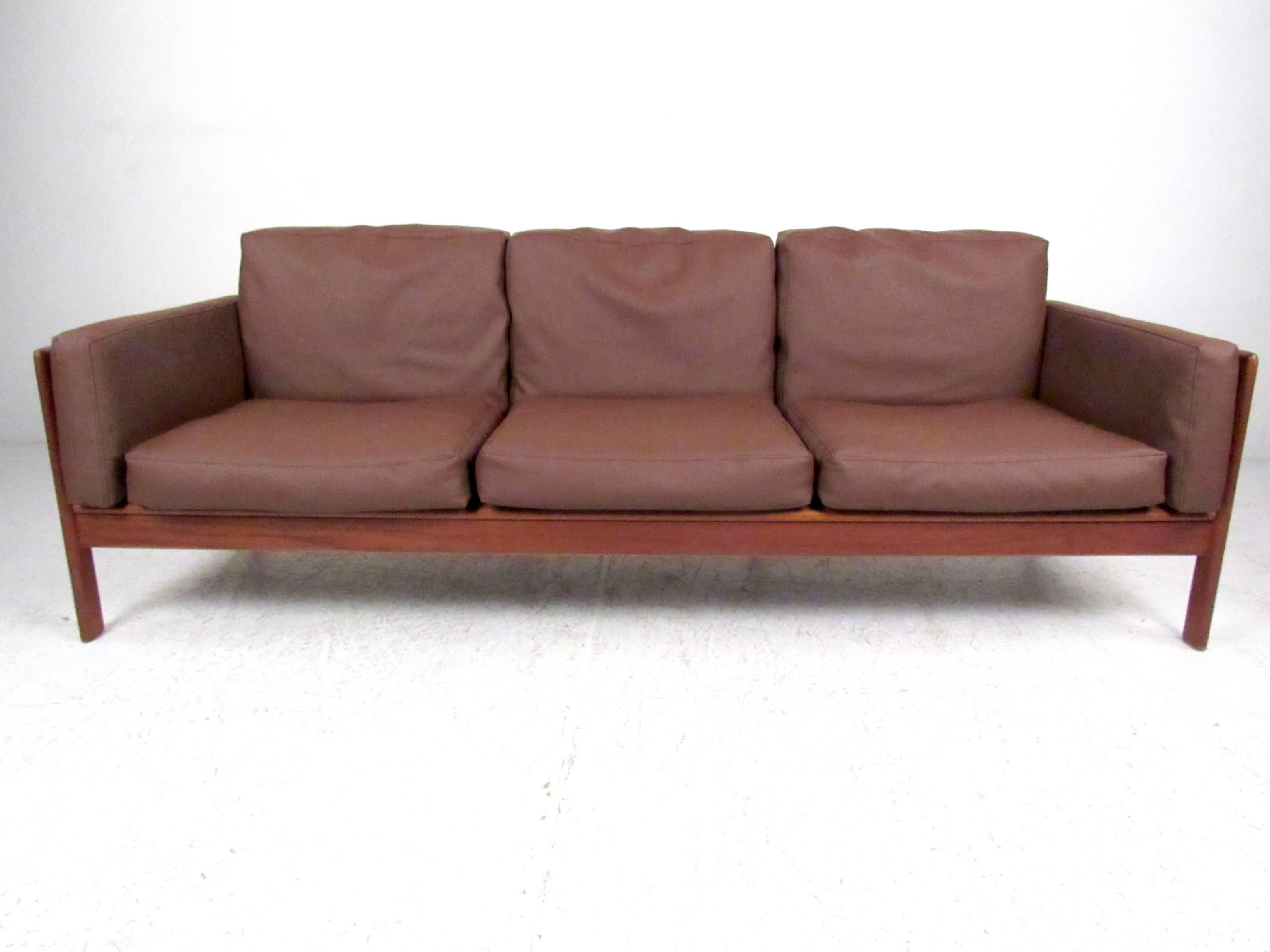 This stylish Mid-Century Modern sofa by Komfort offers seating for three and impressive solid teak frame. Made in Denmark, this beautiful sofa offers comfortable seating with clean, modern lines. Quality construction, please confirm item location