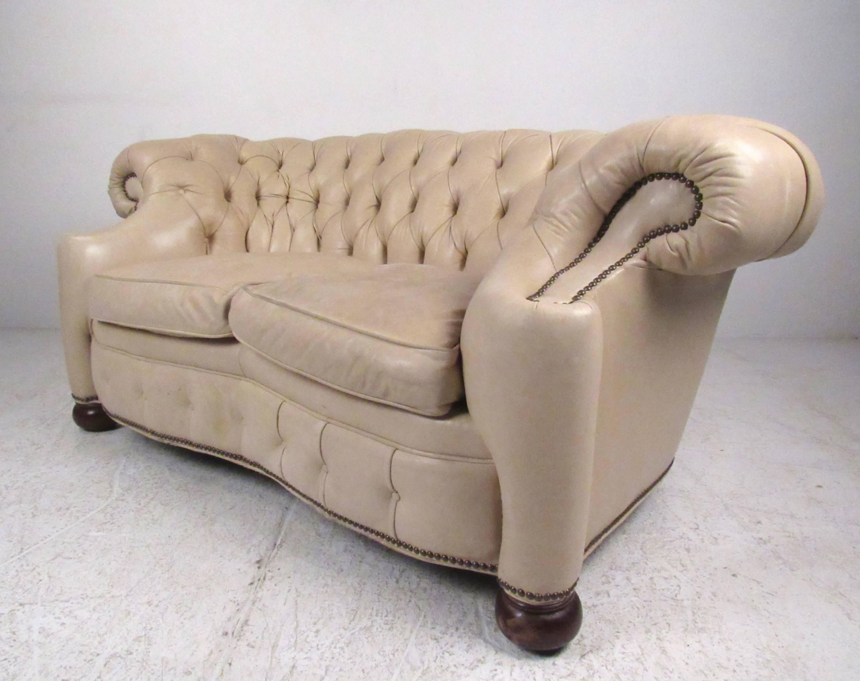 This stylish leather Chesterfield features shapely scrolled arms, tufted leather upholstery, and unique brass details. The two seat sofa by Old Hickory Tannery makes an impressive visual statement without sacrificing comfort. Please confirm item