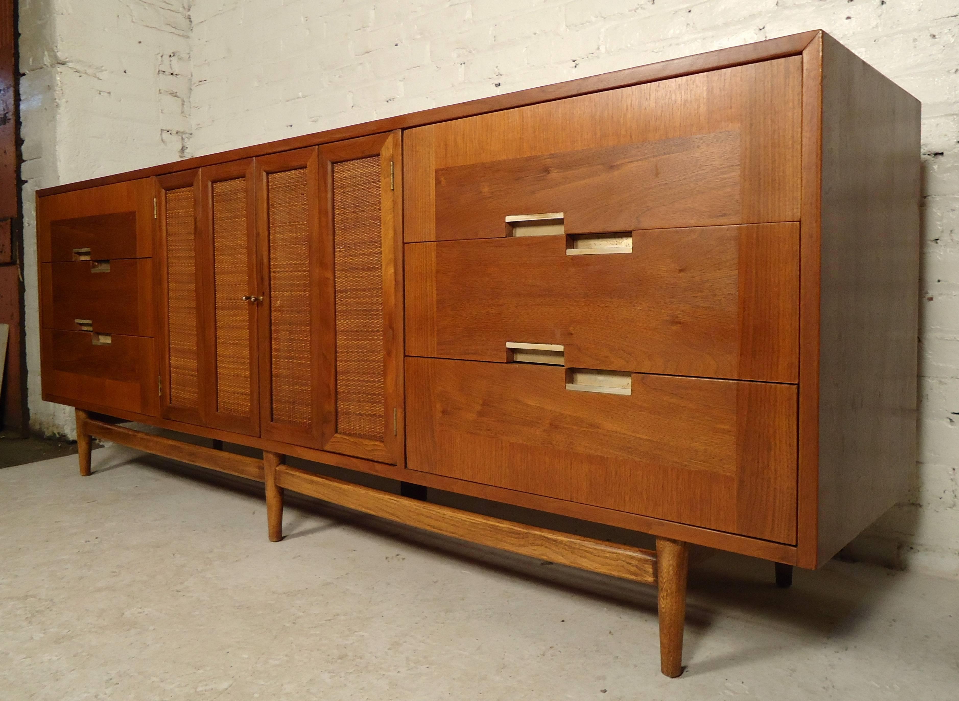 Beautiful long vintage-modern credenza by Martinsville features rich walnut grain, nine pull-out drawers, metal handles and a set of wicker front doors all on sturdy wooden legs.

Please confirm item location (NY or NJ).