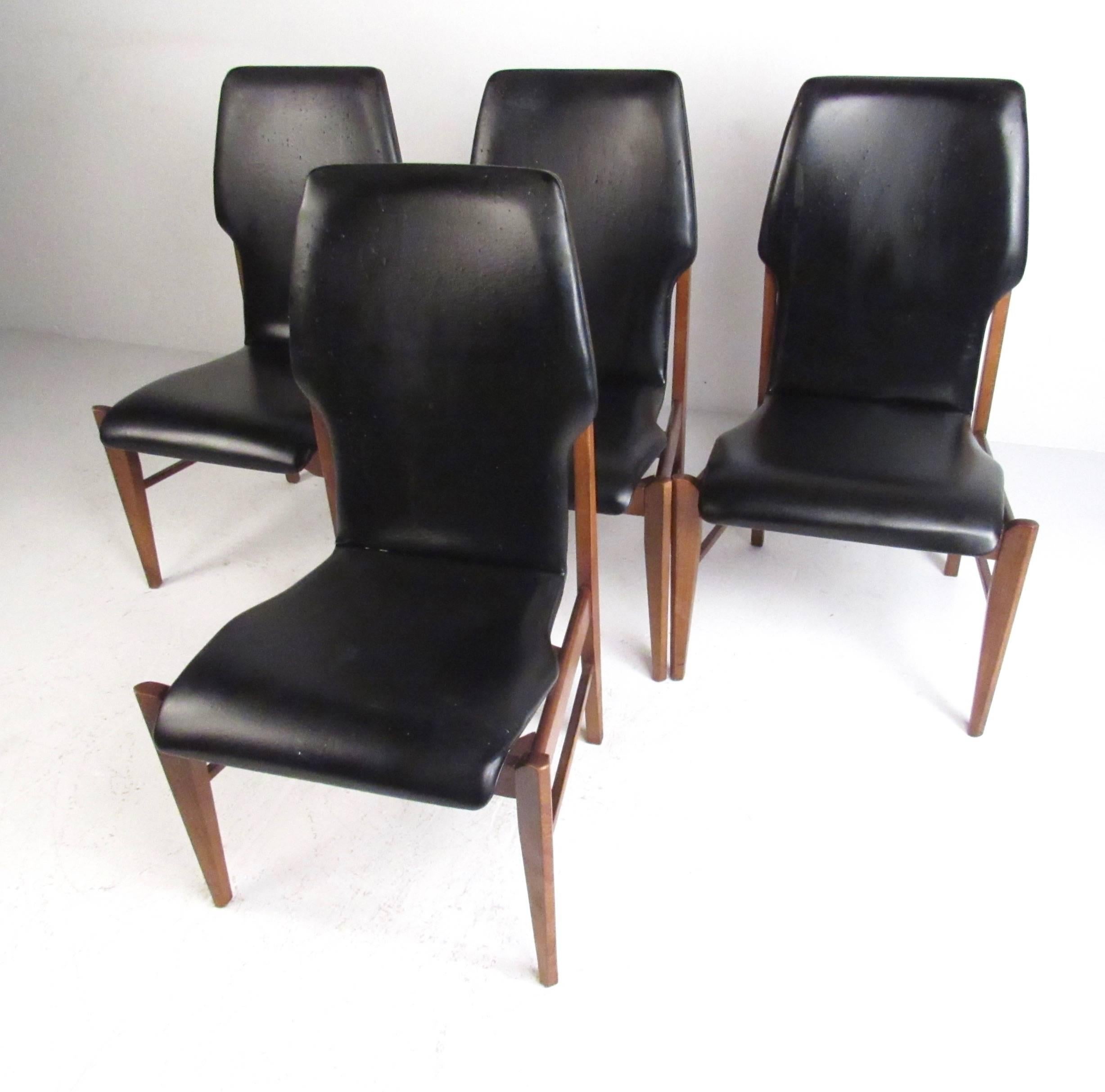 This stylish set of four matching dining chairs offer a shapely vinyl covered seat, with comfortable high backs. Hardwood walnut frames with tapered legs and clean modern lines add to the Mid-Century appeal of these vintage dining chairs. Please