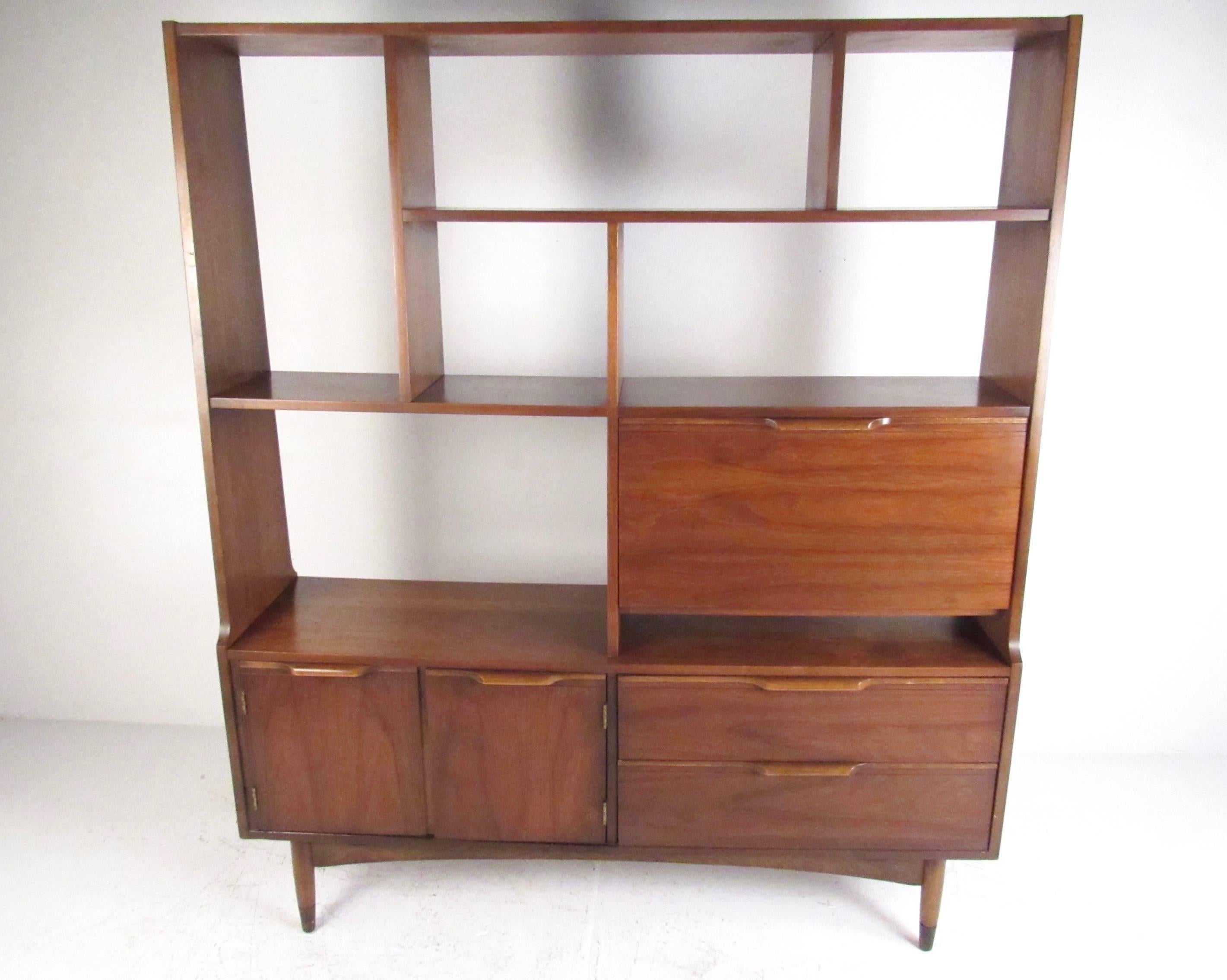 This stylish modern room divider features rich walnut finish, sculpted handles, and unique open display shelves. Tapered legs with brass sabots add to the Mid-Century Modern charm of the piece, while spacious storage cabinets and drawers make it