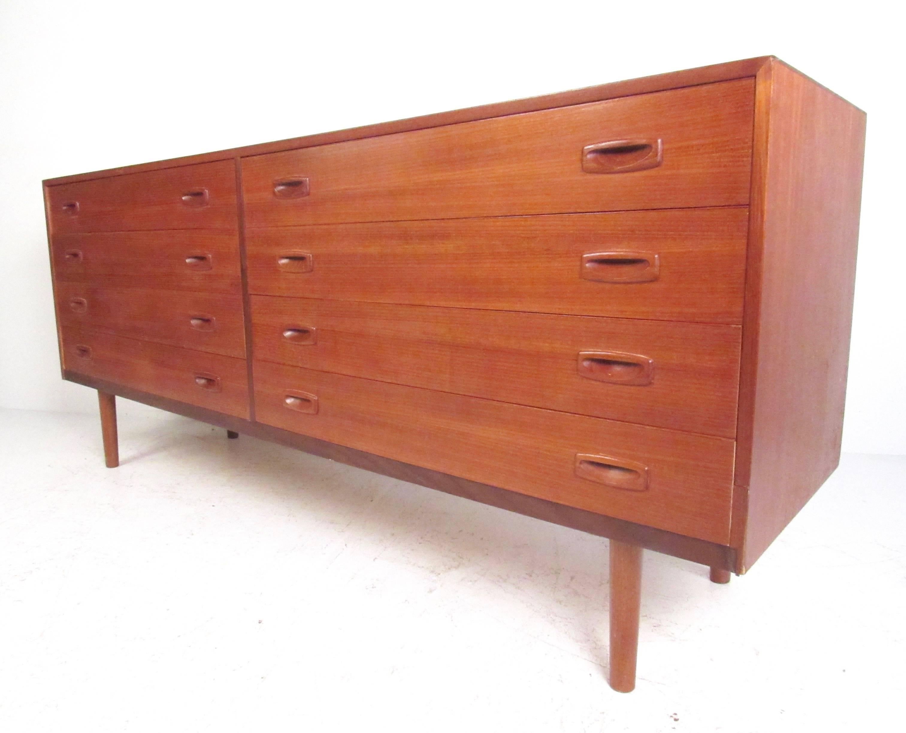 This well crafted Danish modern low bedroom dresser with carved teak drawers, banded teak front, and spacious dovetailed drawers. Please confirm item location (NY or NJ).