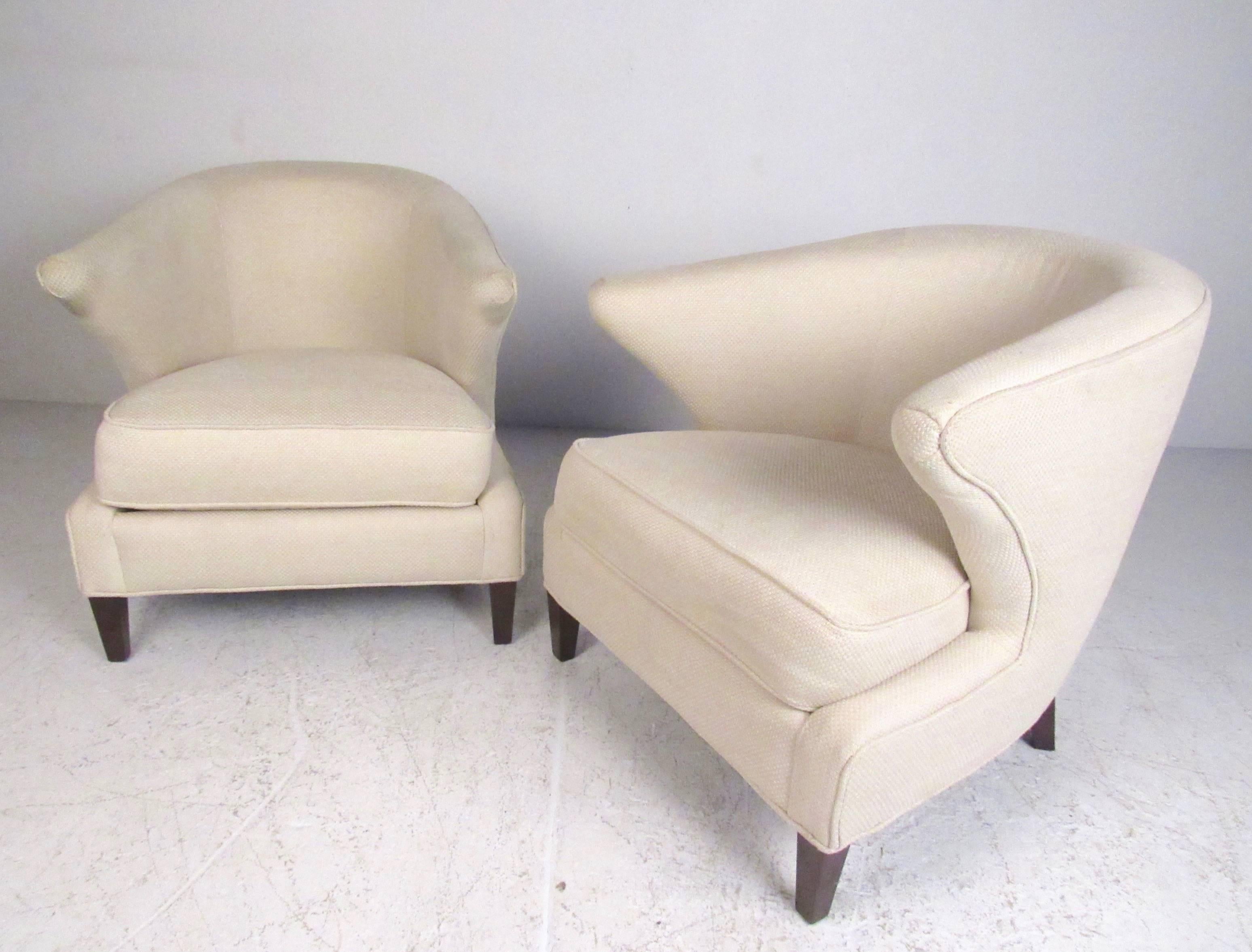 This stylish pair of upholstered lounge chairs feature sculpted barrel back seats with unique arms and hardwood legs. Thayer Coggin combines clean, modern design with comfort and style as illustrated in this pair. Please confirm item location (NY or