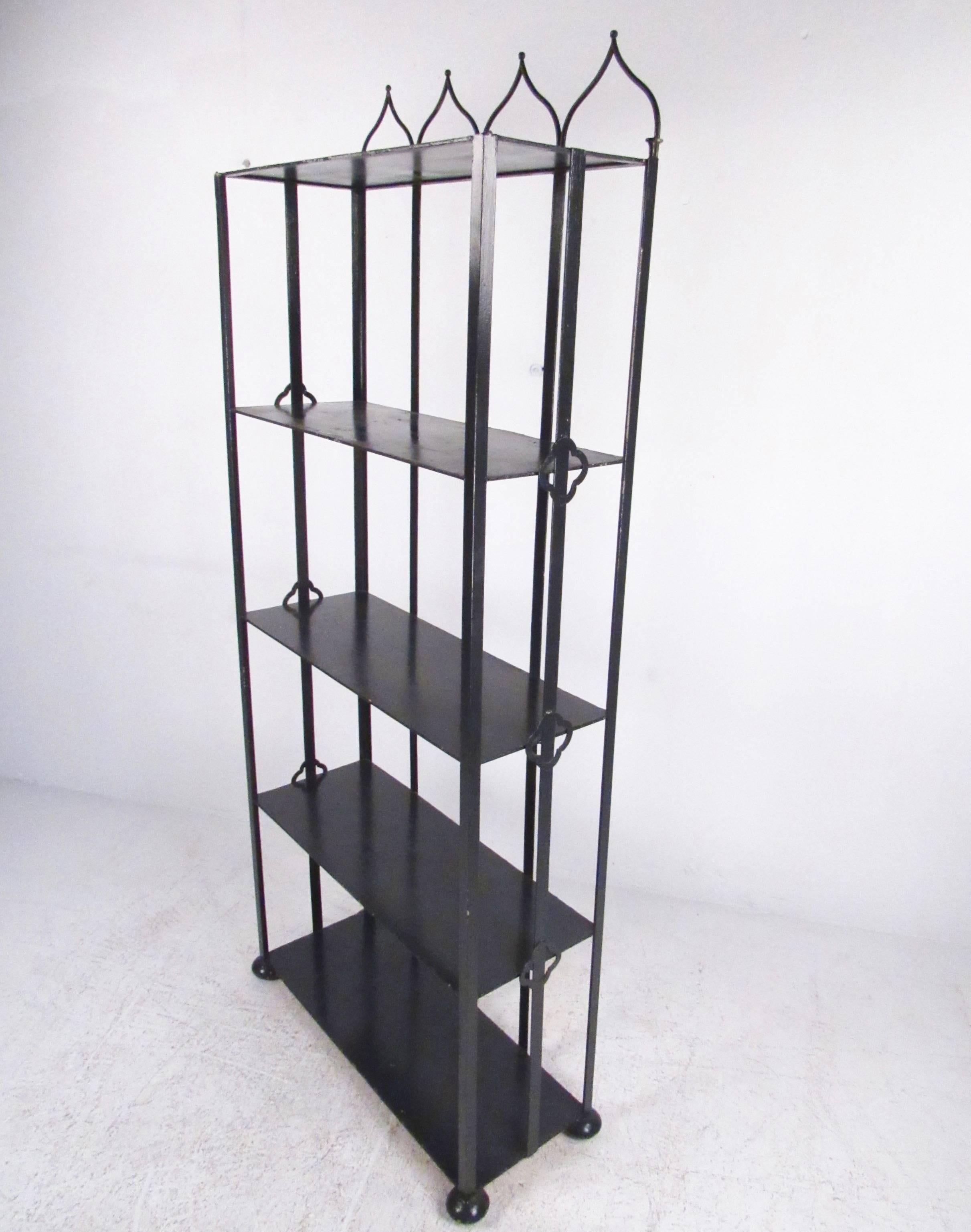 This tall and stylish metal bookshelf features ornate pointed top and decorative trim and feet. Four spacious shelves for display or storage use, this vintage Industrial book case makes a unique addition to any interior. Please confirm item location