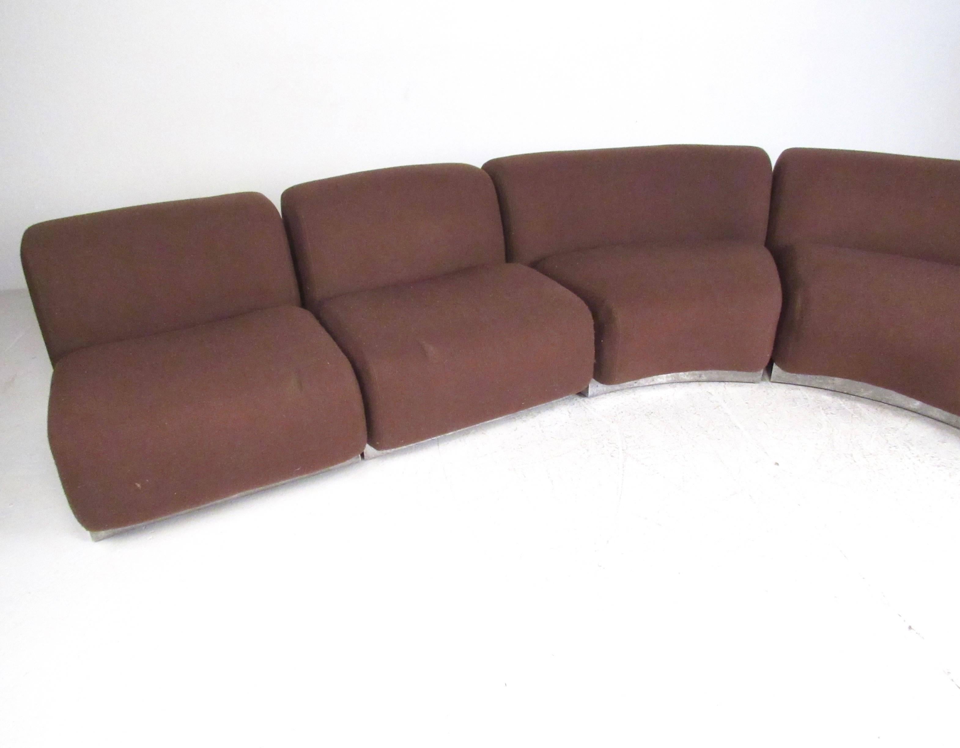 This unique Mid-Century Modern five piece sectional sofa features a low-profile club design and plush upholstered seats. Stylish metal trim covers a hardwood base, while vintage brown upholstery adds to the mid-century appeal. This impressive