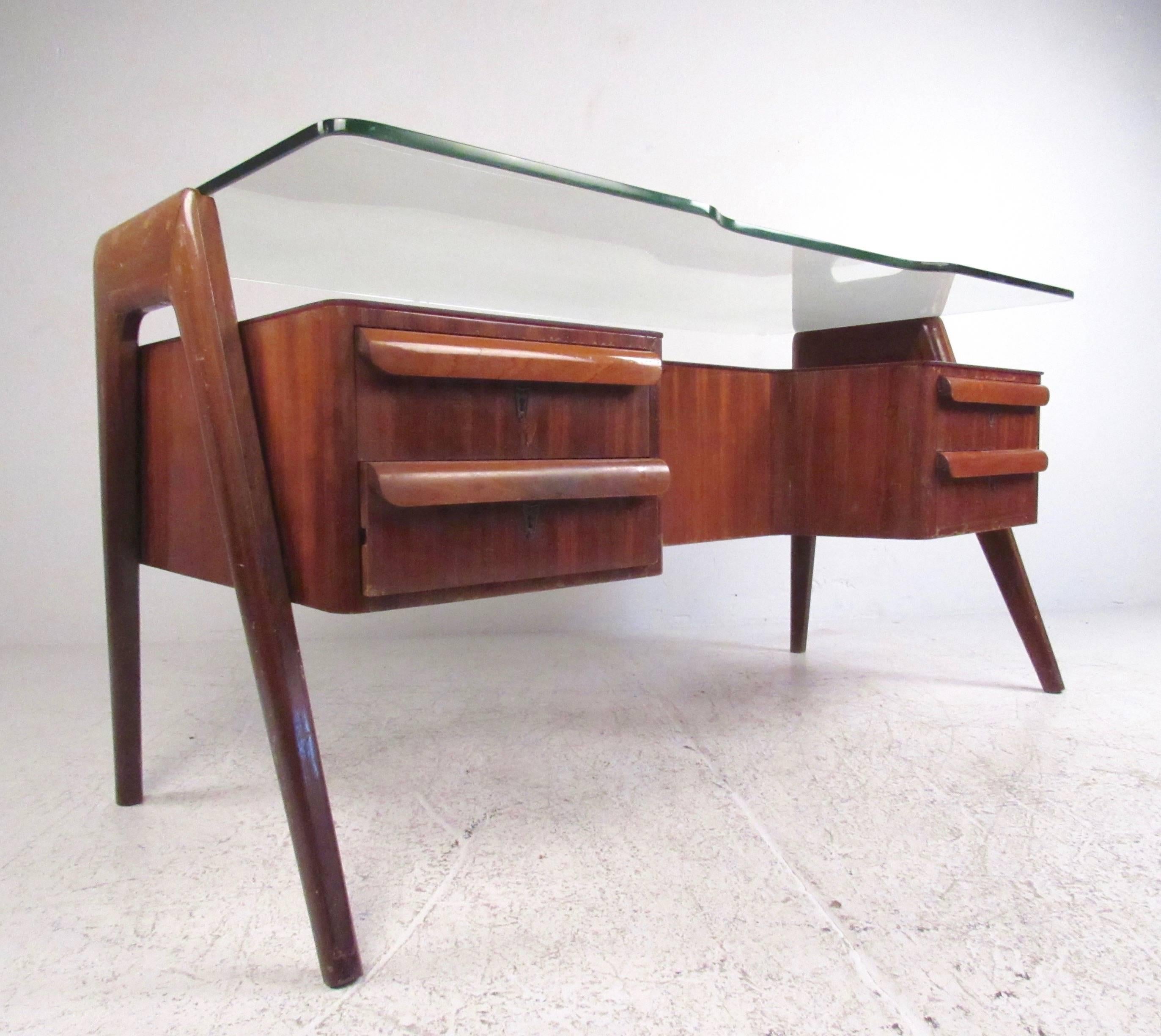 This stylish Italian modern desk features sculptural hardwood construction with cutaway construction and vintage lacquer finish. Carved drawer pulls, double-glass tops, and an impressive amount of work and storage space make this Vittorio Dassi