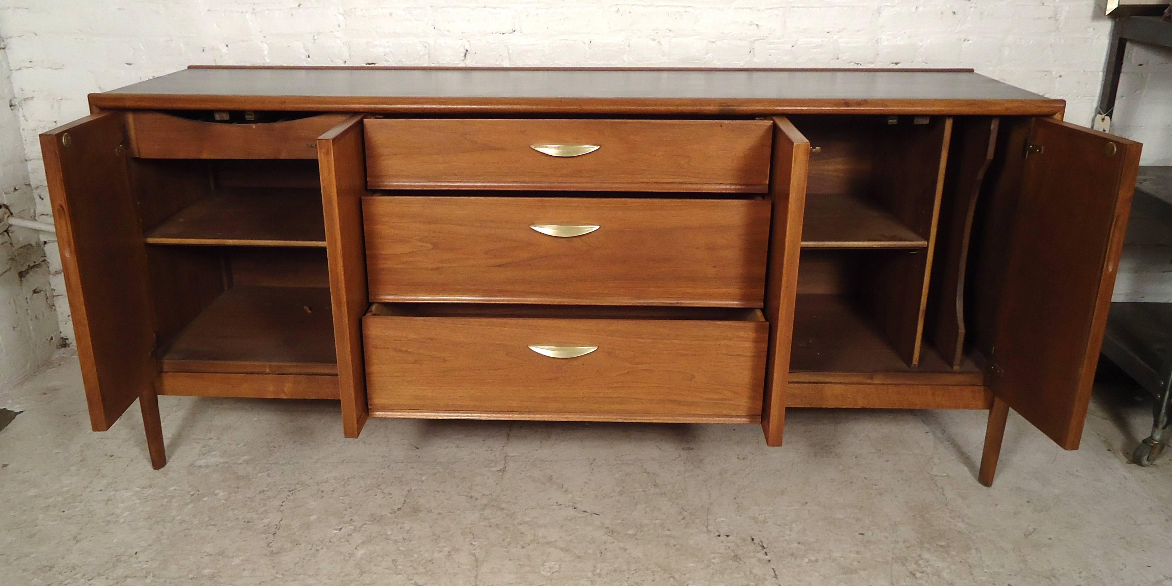 Very stunning vintage modern credenza features two-door storage cabinets on each side, three drawers with brass handles, on a set of four sturdy legs.

Please confirm item location (NY or NJ).
