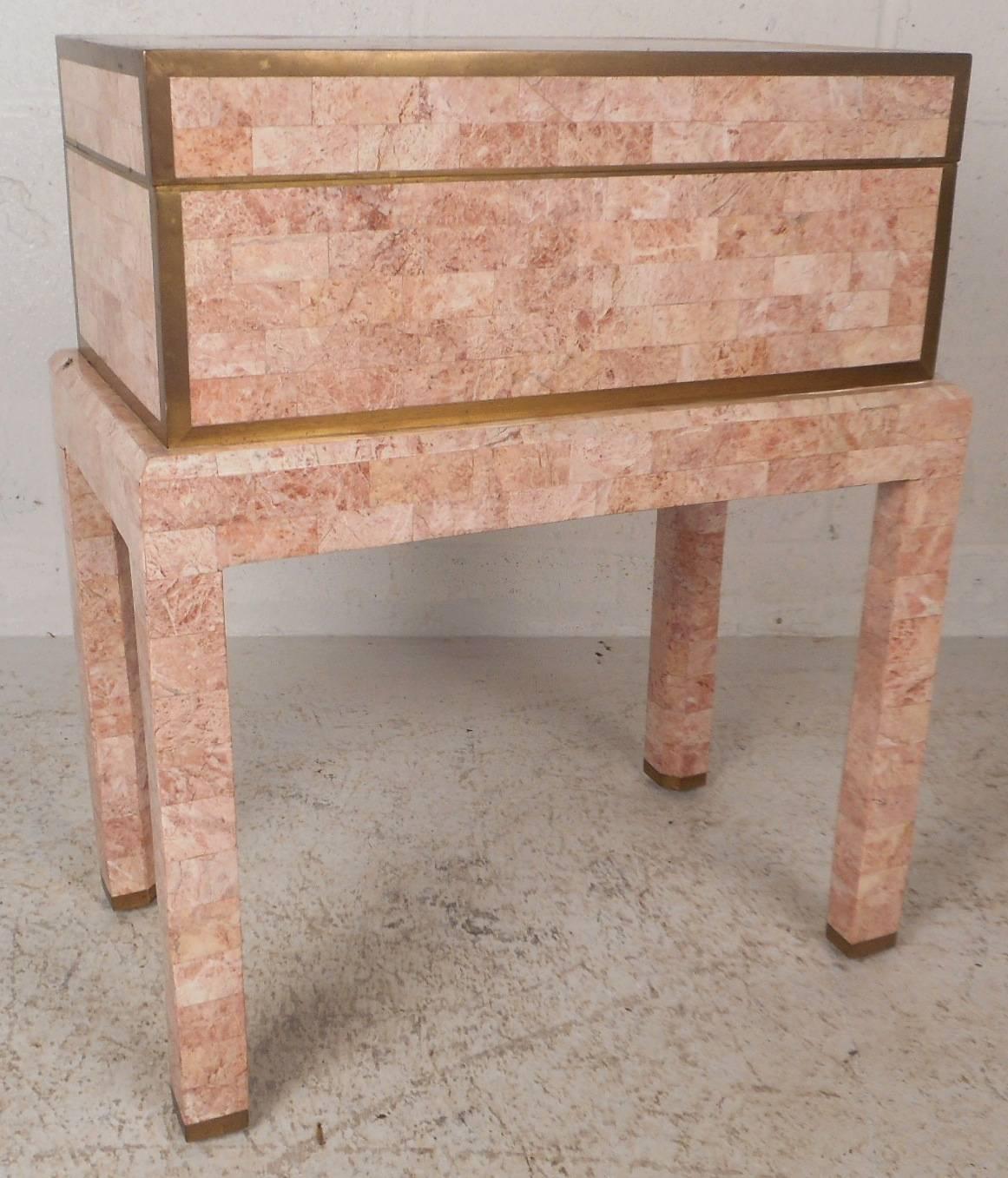 Elegant vintage modern box by Maitland-Smith is made of pink tessellated stone with brass inlay around the edges. Stylish design sits on top of four legs offering convenient access. The unique design has a top that opens up to a gorgeous wood grain