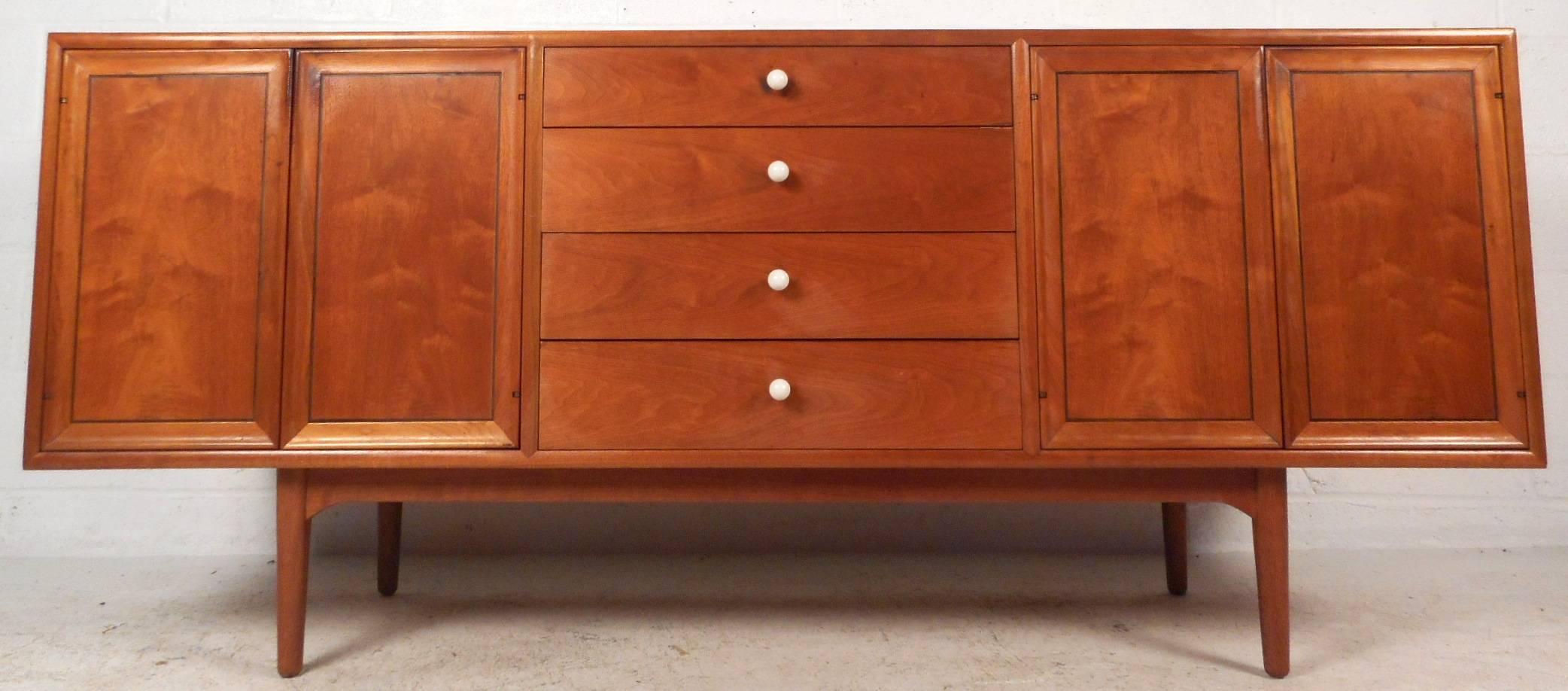 This beautiful vintage modern sideboard by Drexel features an abundance of storage space within its many drawers and compartments. Sleek design with four large drawers in the center and two cabinets that open up to unveil shelves. The unique round