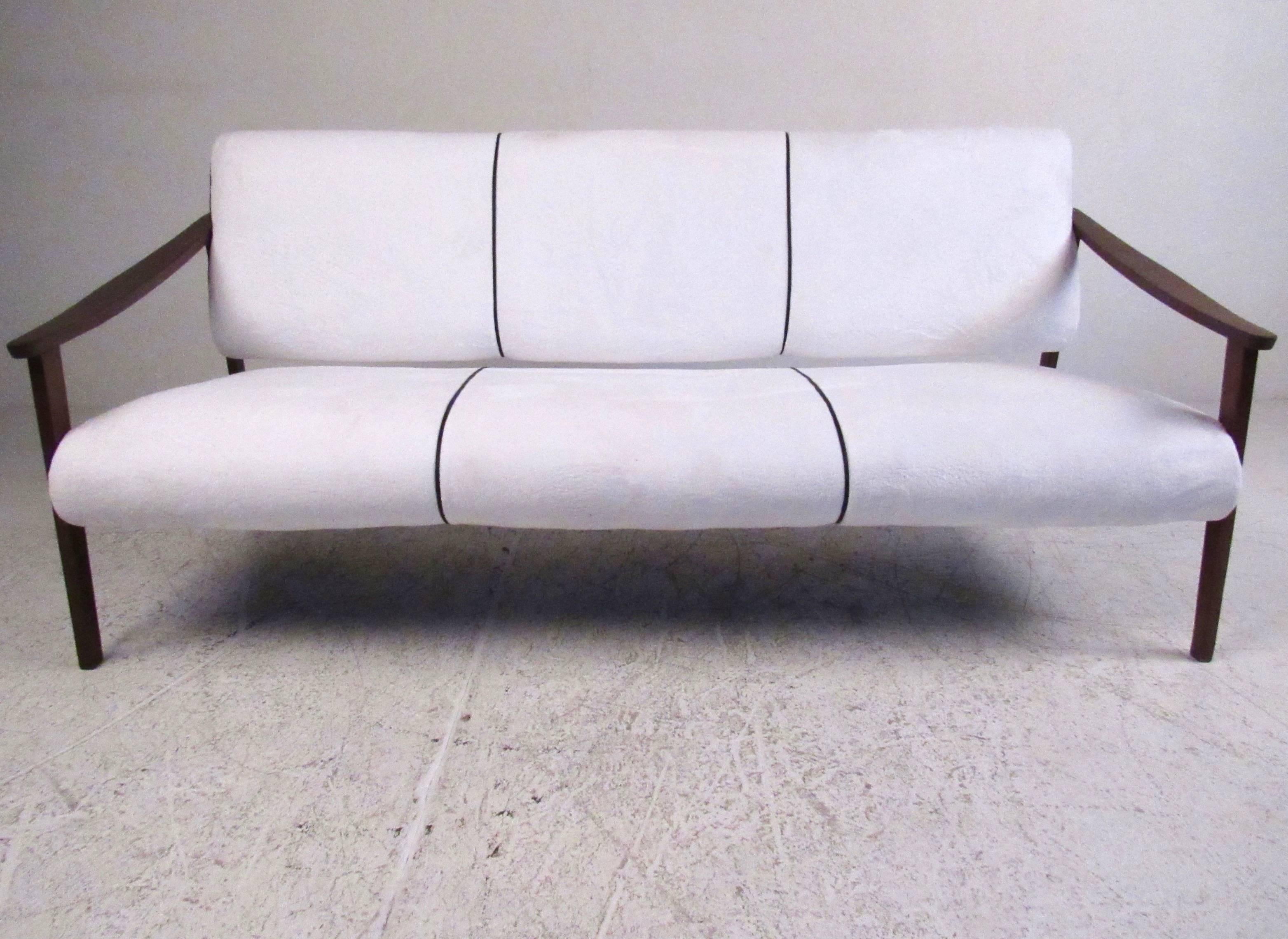 This beautiful Mid-Century style sofa makes a stylish addition to any interior and offers seating for three with sculpted hardwood frames. Two tone upholstery includes black vinyl accents on the side and back. Please confirm item location (NY or NJ).