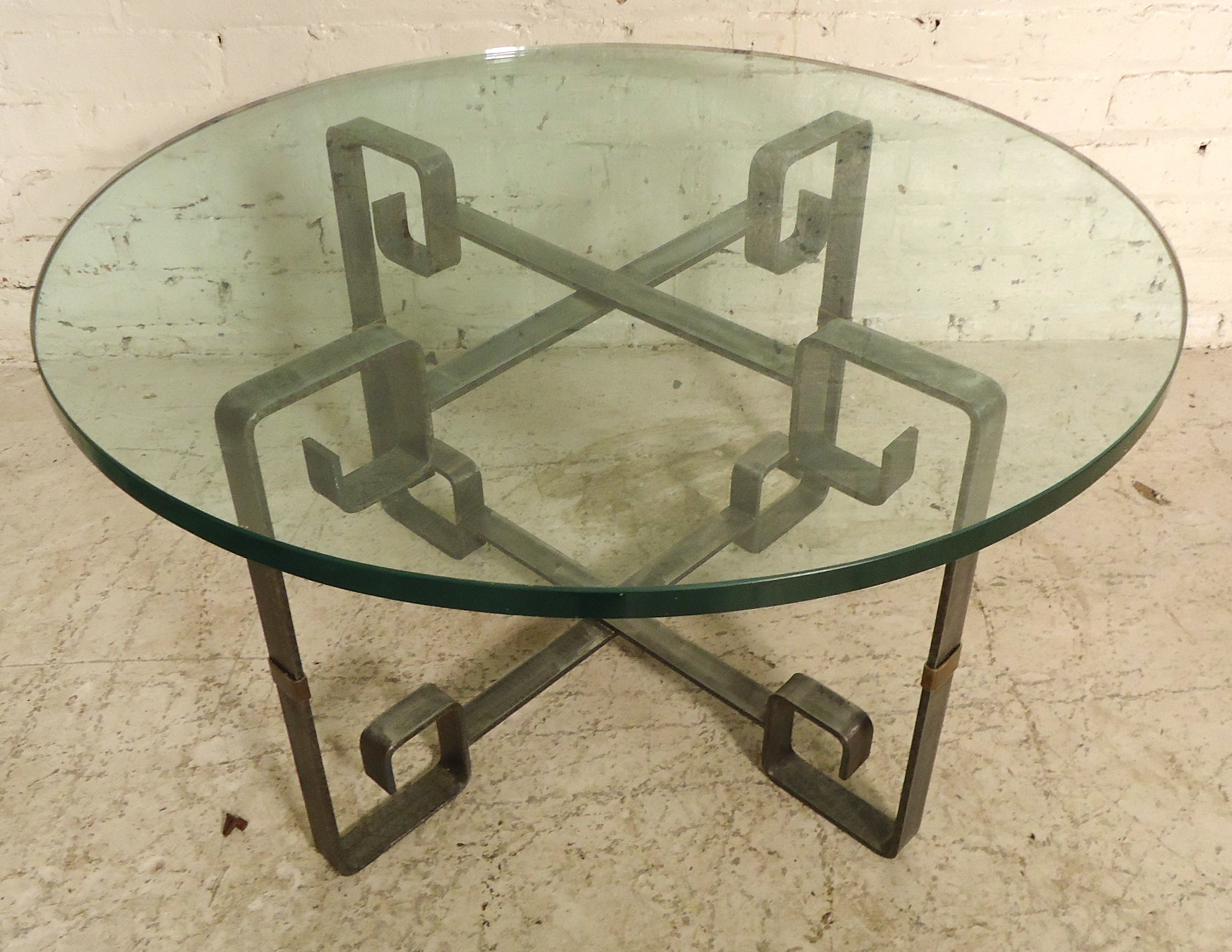 Table unique en métal avec plateau rond en verre épais. Finition de style métal nu avec un design de clé grecque et des accents en laiton.
La base est de 24 x 24